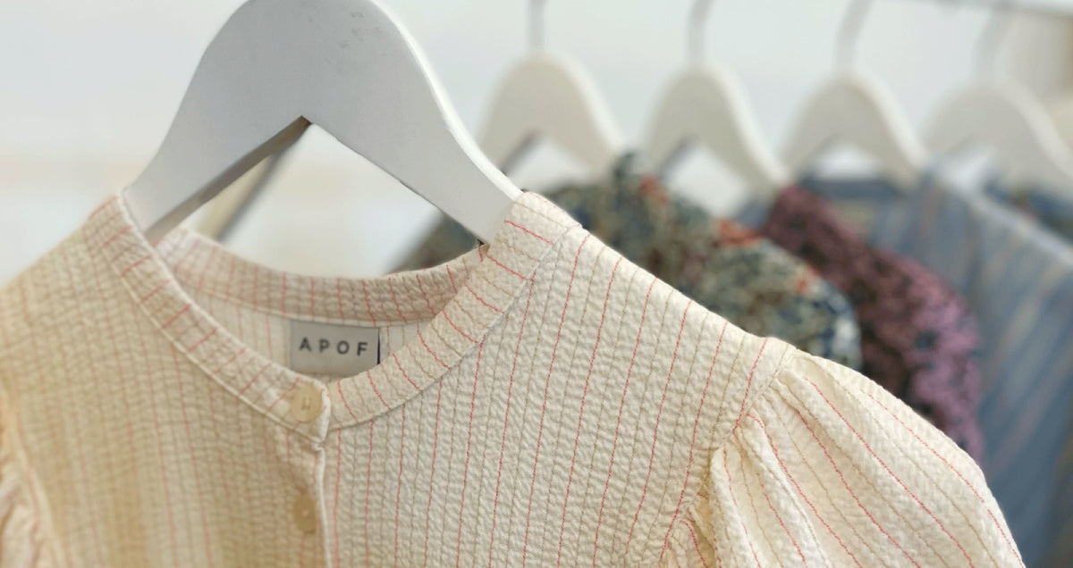 APOF shirts in different colors and fabrics hanging on a rack