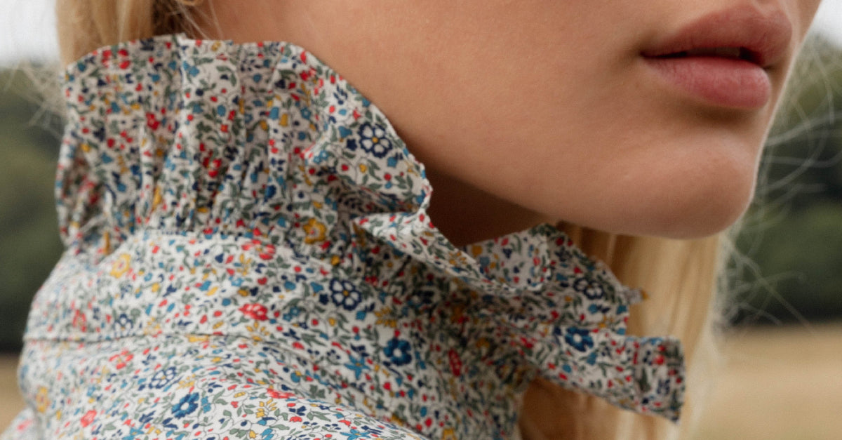 Woman in multi-colored floral blouse with frilled stand collar