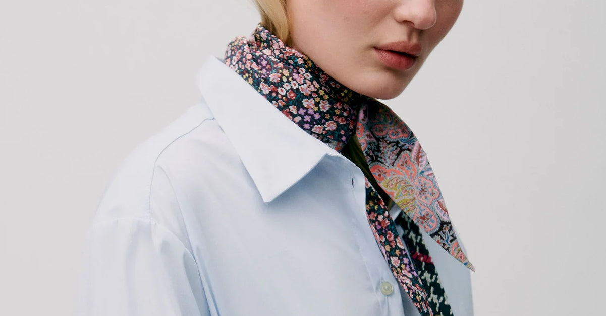 Woman in light blue shirt and floral patterned scarf