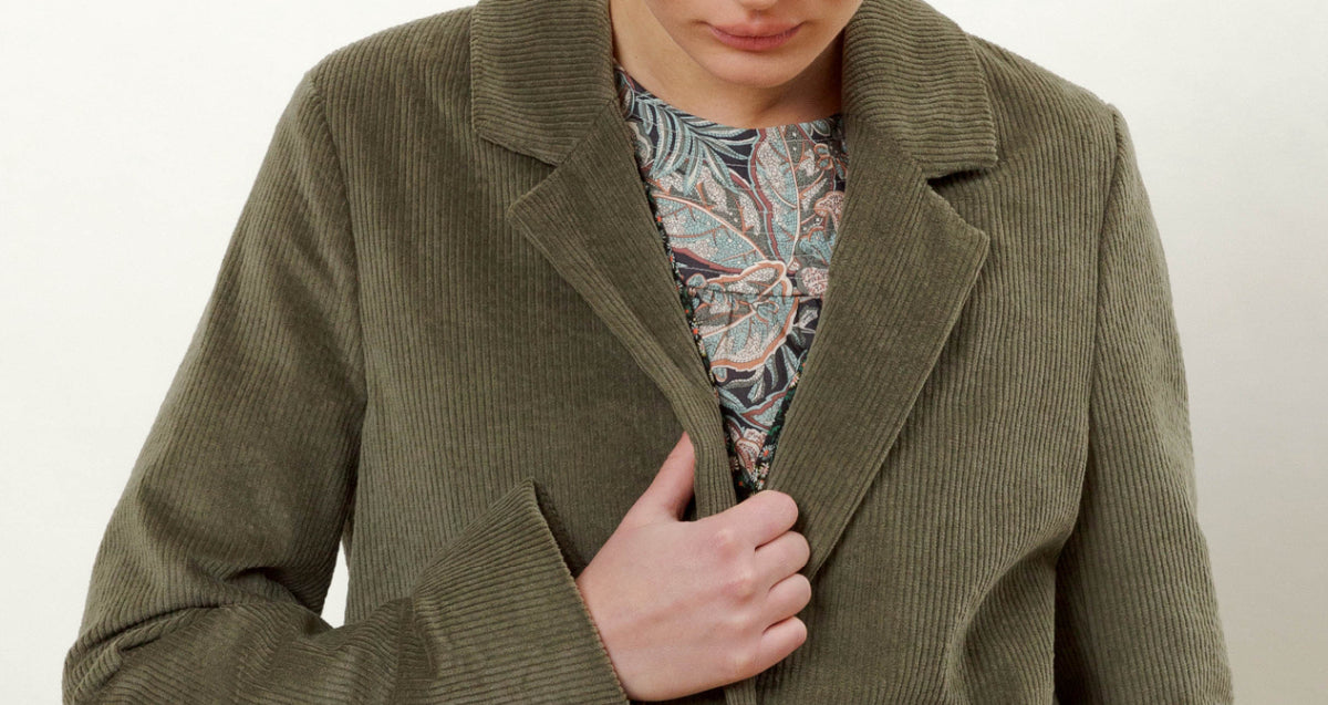 Woman in green corduroy blazer and paisley patterned blouse
