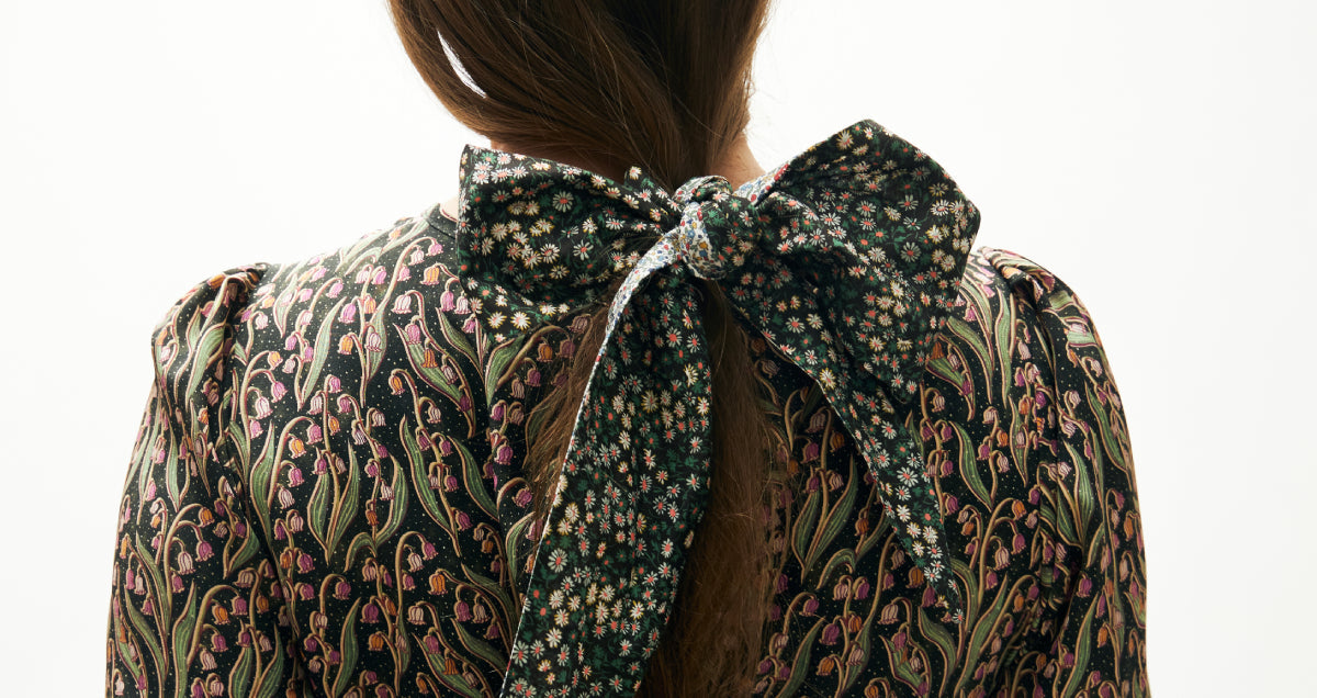 Woman in floral party dress with floral scarf tied around hair