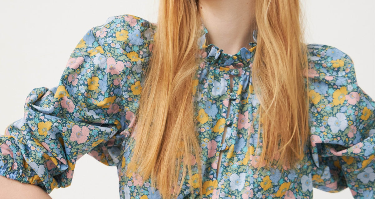 Woman in multi-colored floral patterned summer dress with puff sleeves and frilled collar