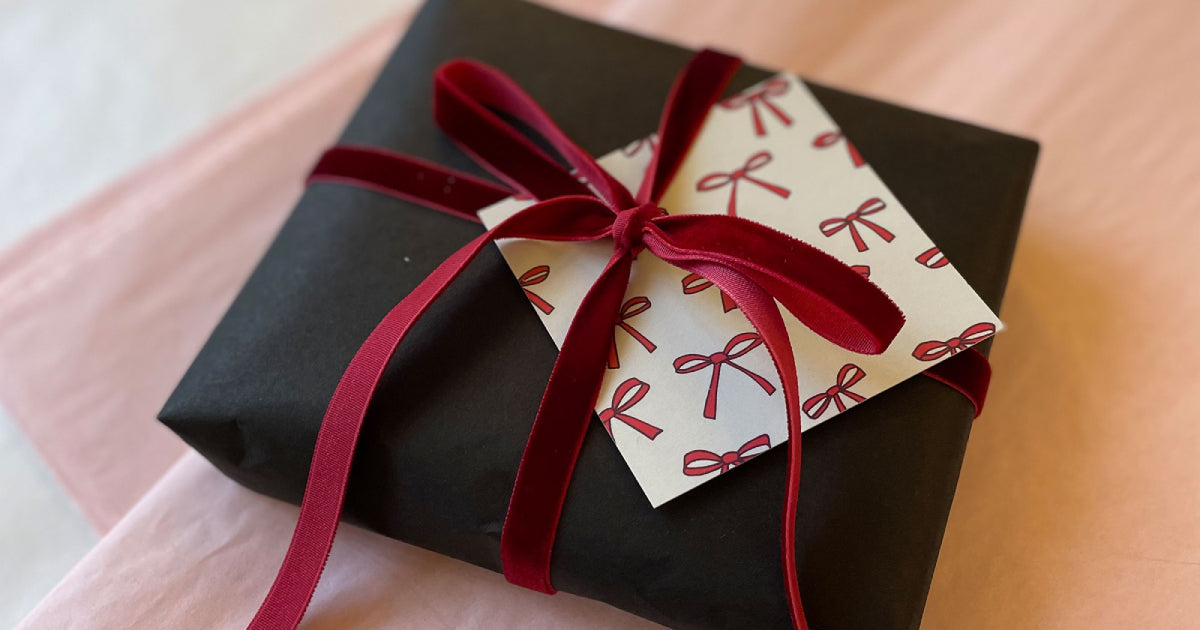 Gift with black wrapping red velvet ribbon and greeting card with red bows