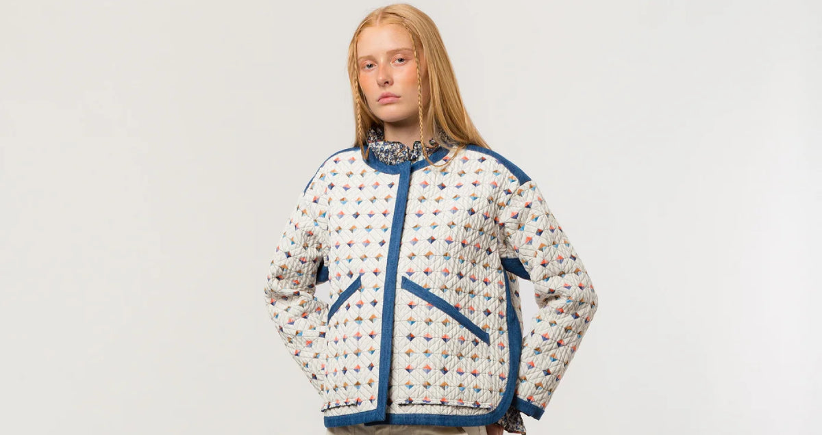 Woman in white quilted jacket with multi-colored check pattern and blue pipings