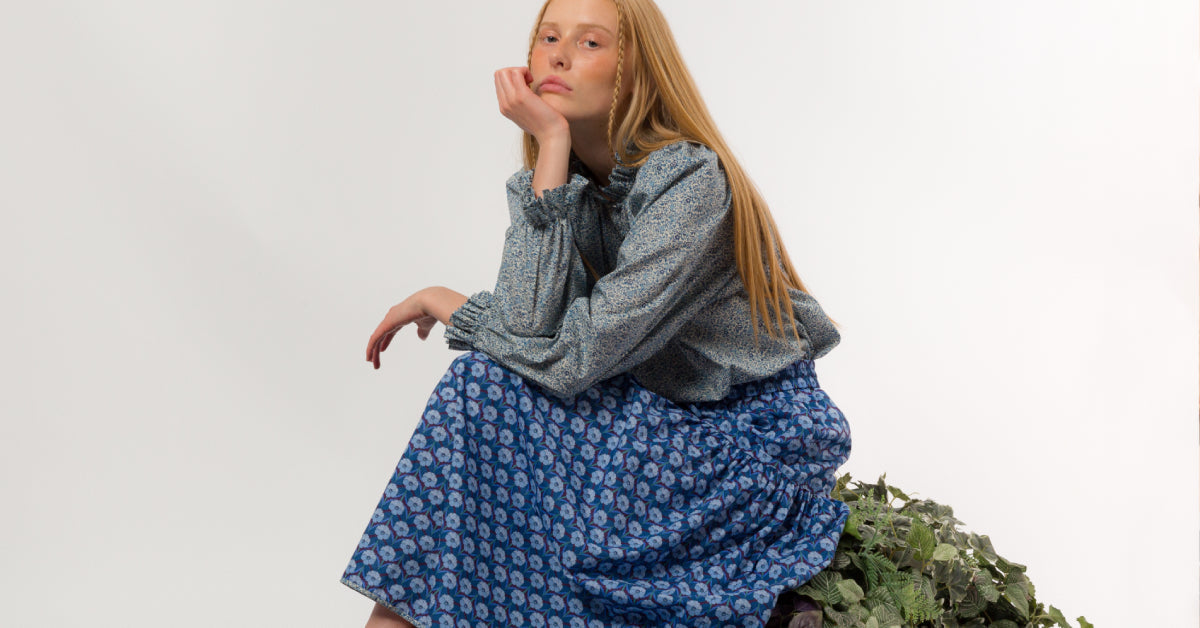Woman in long blue Liberty cotton shirt with blue flower pattern and long sleeved blouse with blue flowers