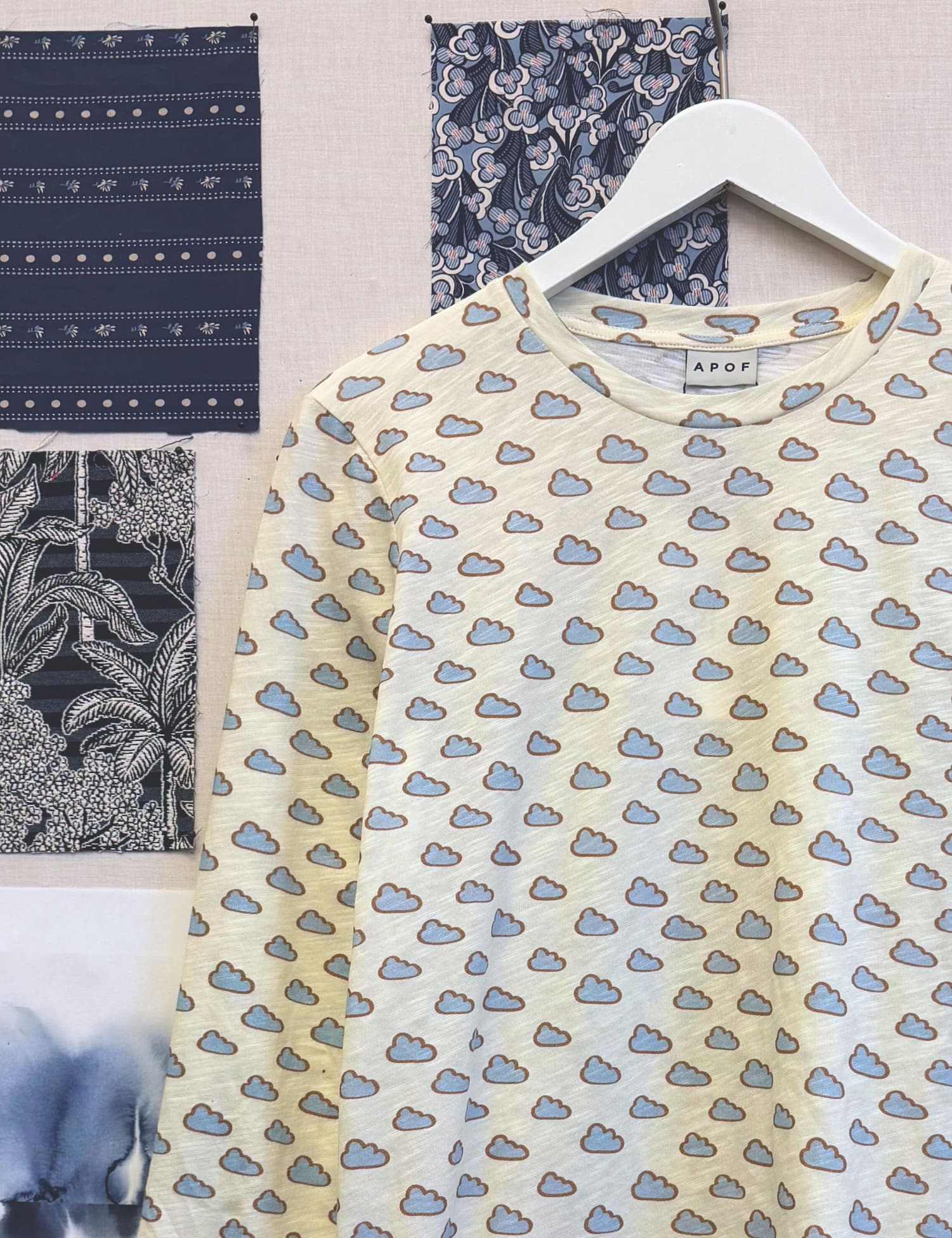 T-shirt with cloud pattern on a hanger with fabric swatches in the background