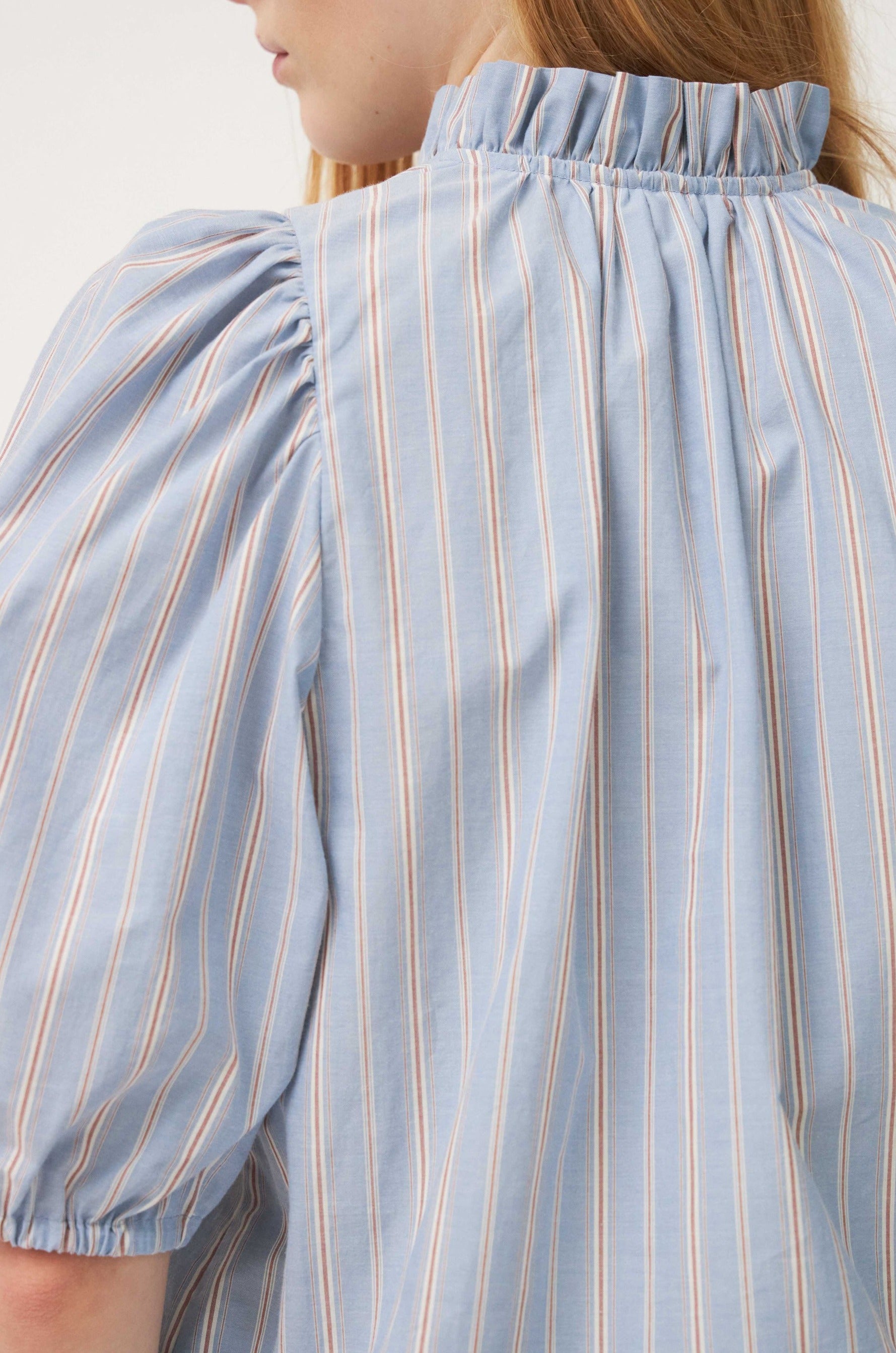 Woman wearing blue striped blouse with frills