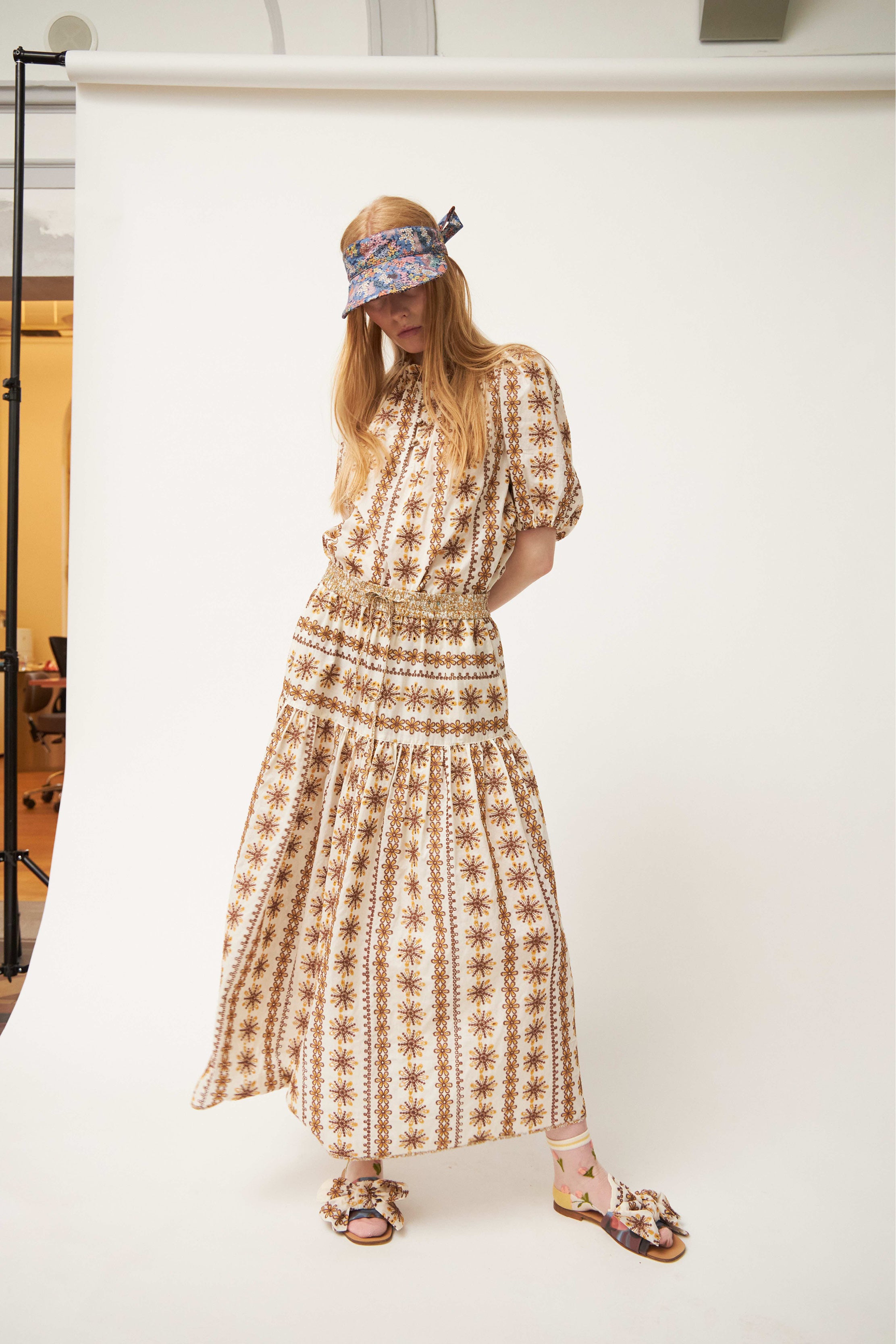 Woman in brown patterned blouse and skirt sandals and hat