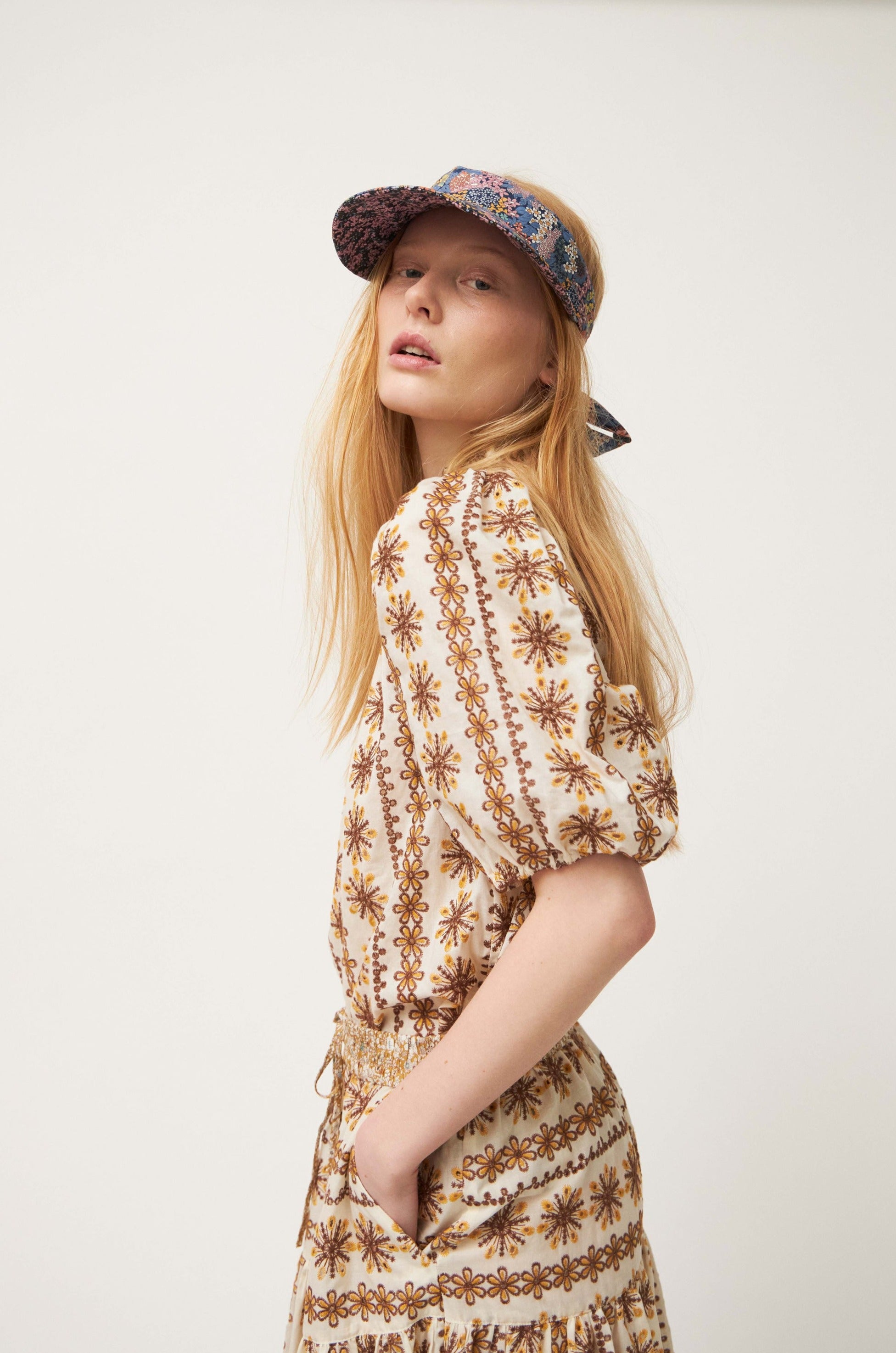 Woman in brown patterned blouse and hat