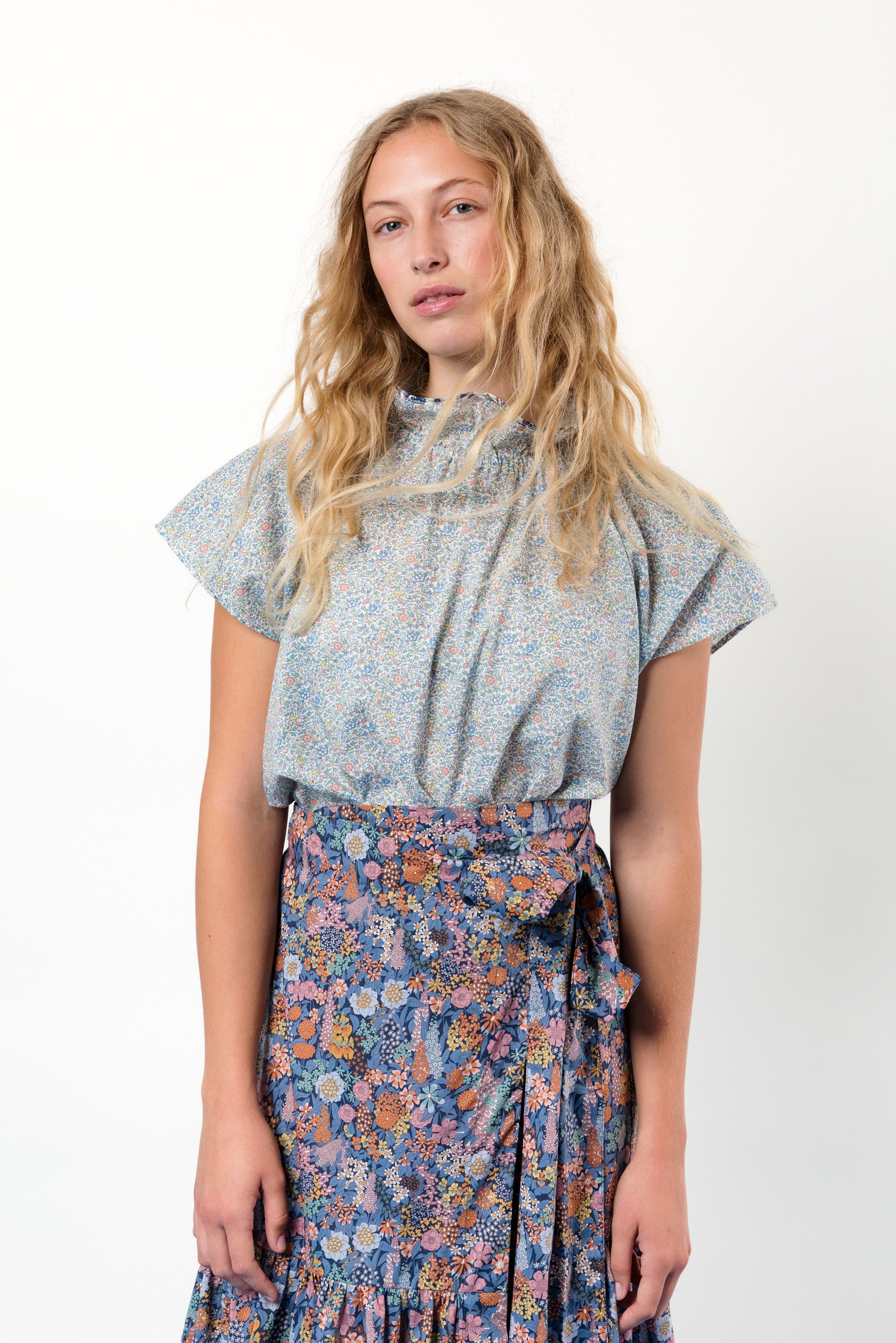 Woman in green blouse and flower patterned skirt