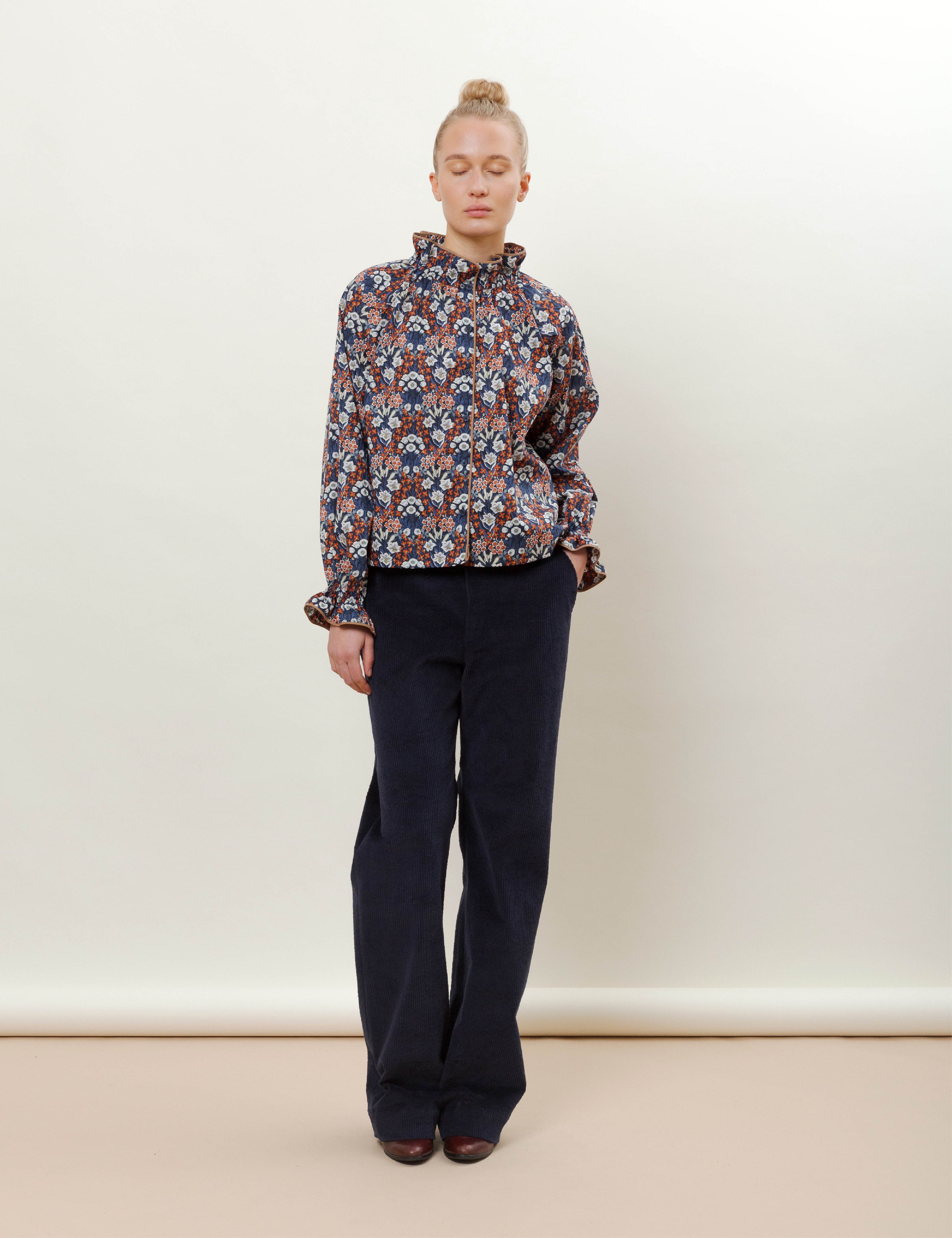 Woman in blue corduroy pants and red white and blue shirt with flower pattern