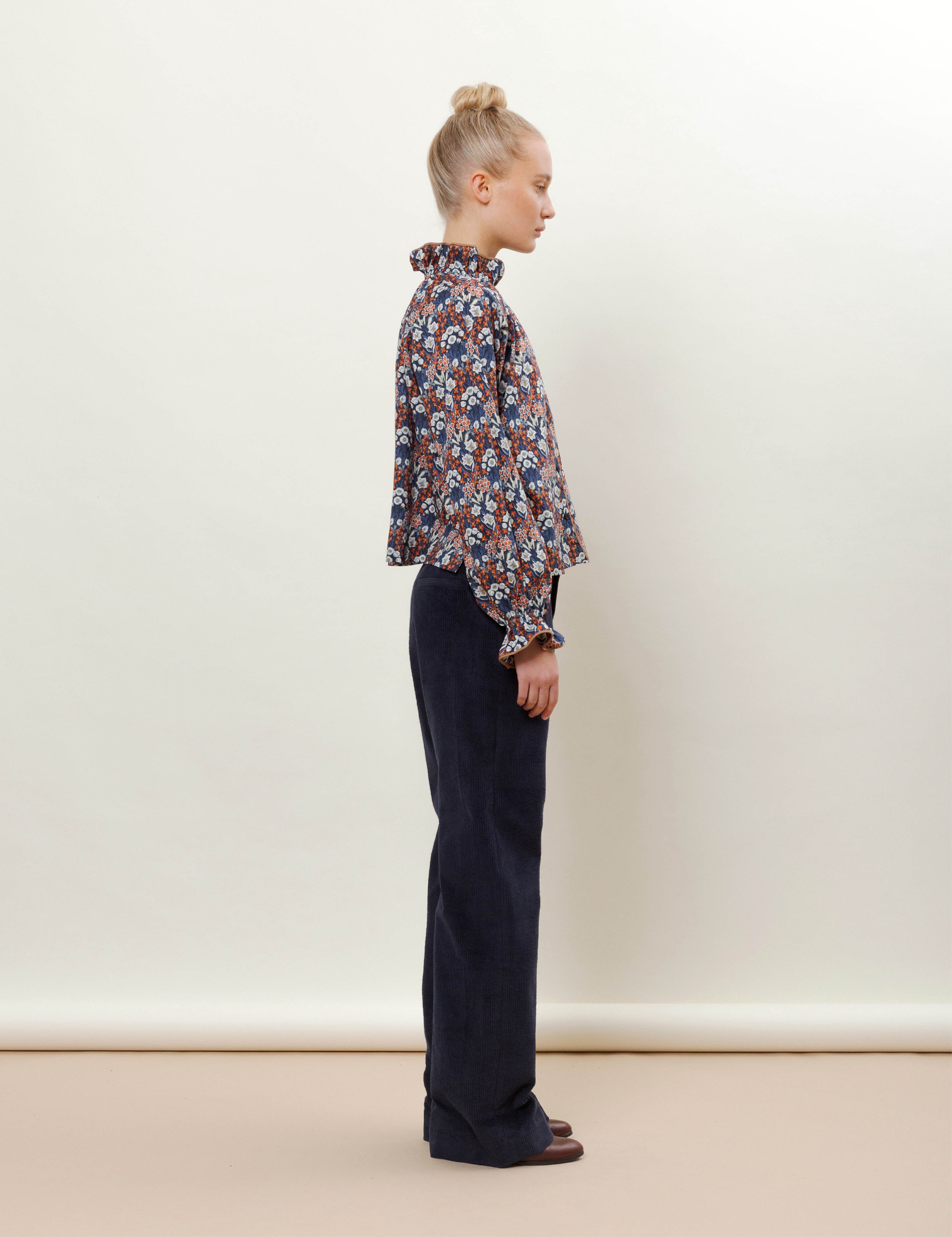 Woman in blue corduroy pants and red white and blue shirt with flower pattern
