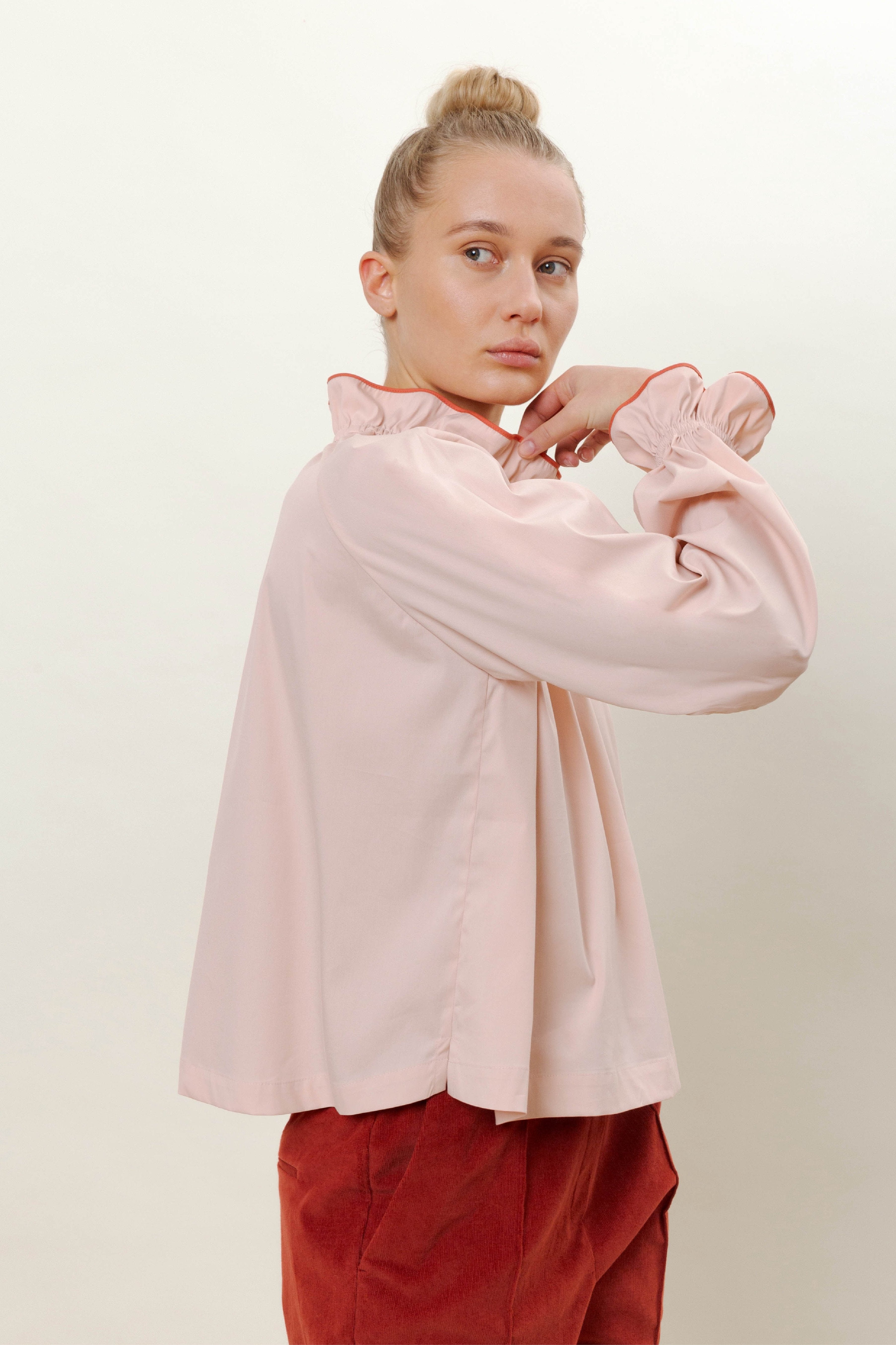Woman in pink long sleeved shirt and red trousers