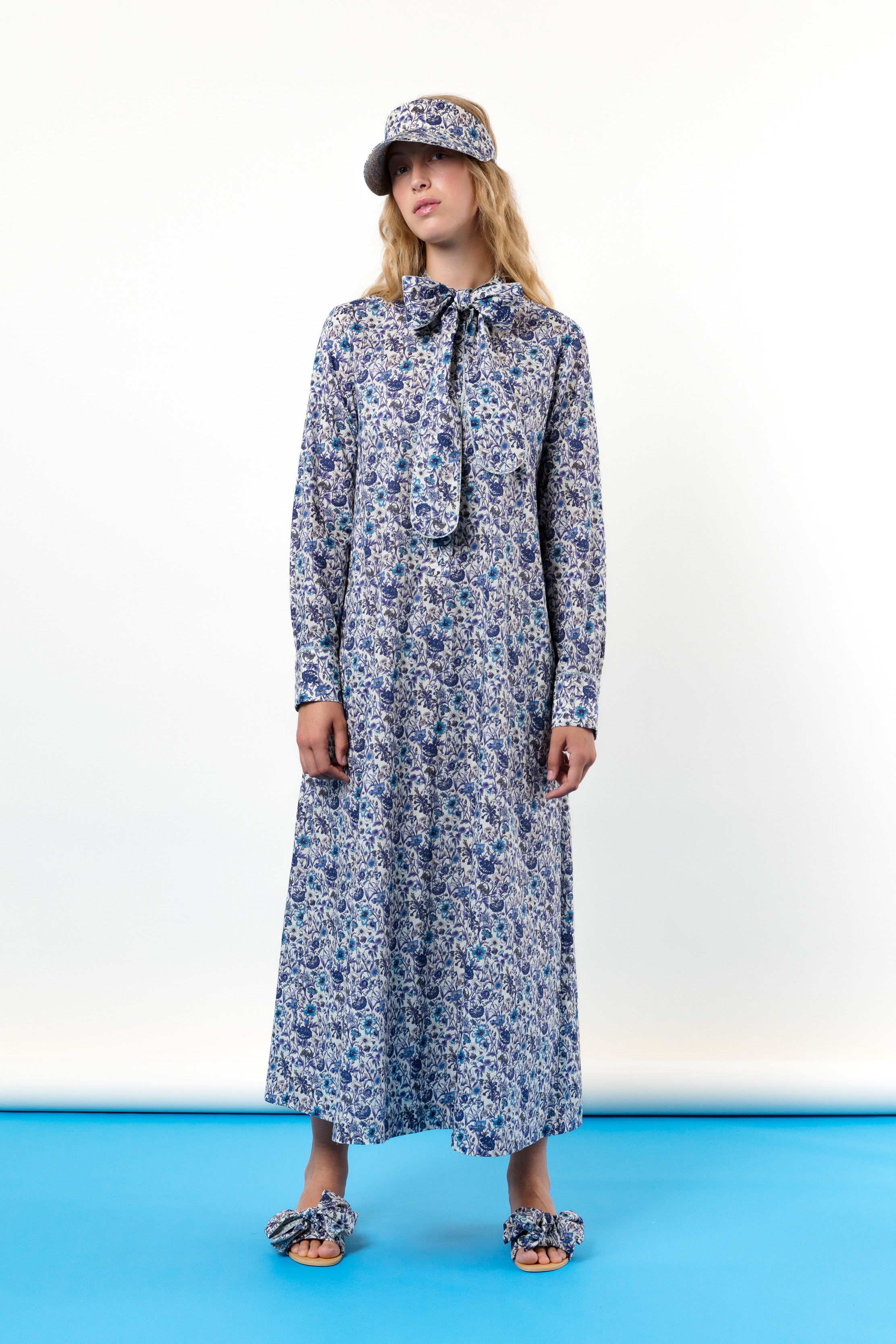 Woman in dress with blue flower pattern, sandals and hat