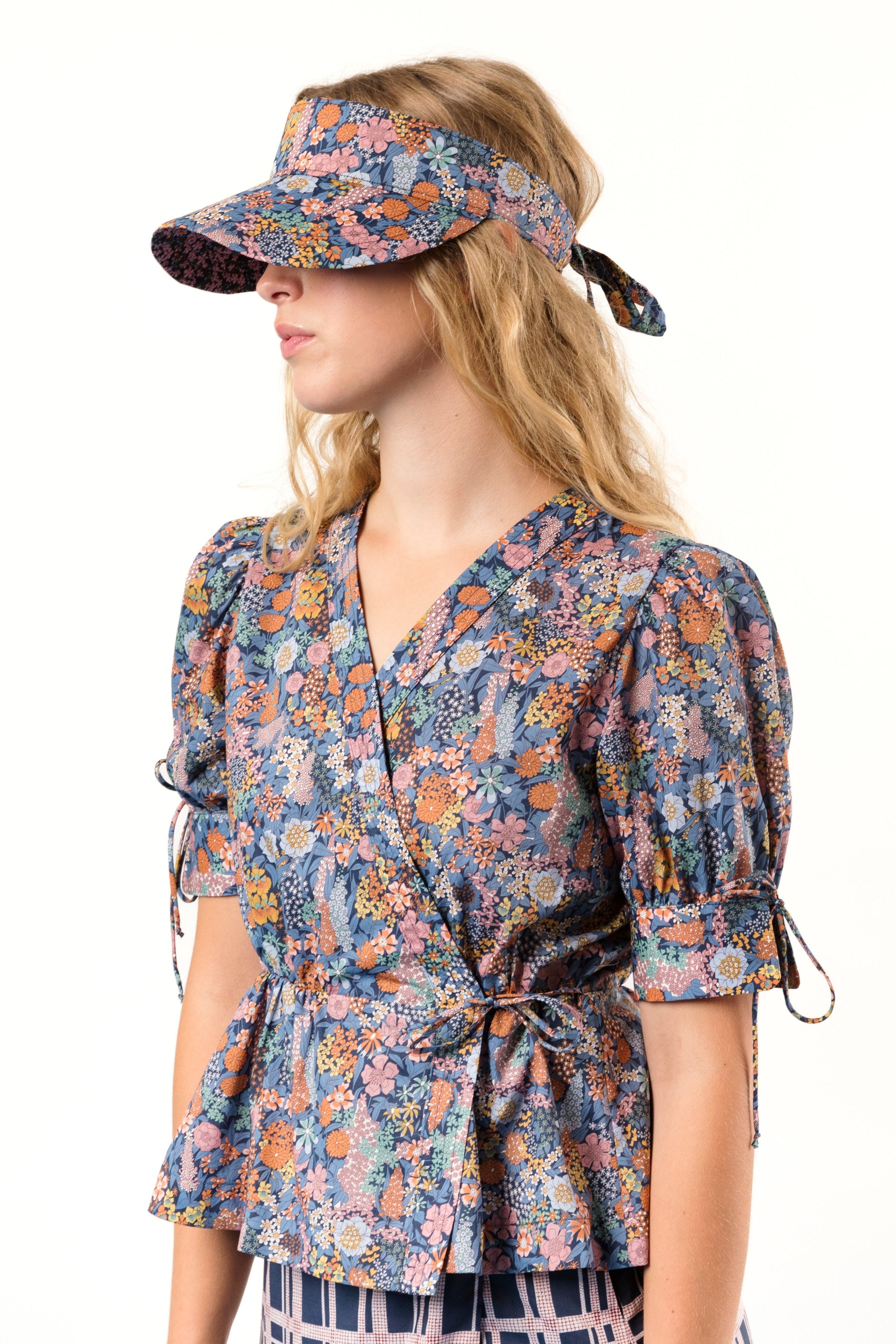 Woman in short sleeved wrap blouse and sun cap with flower pattern