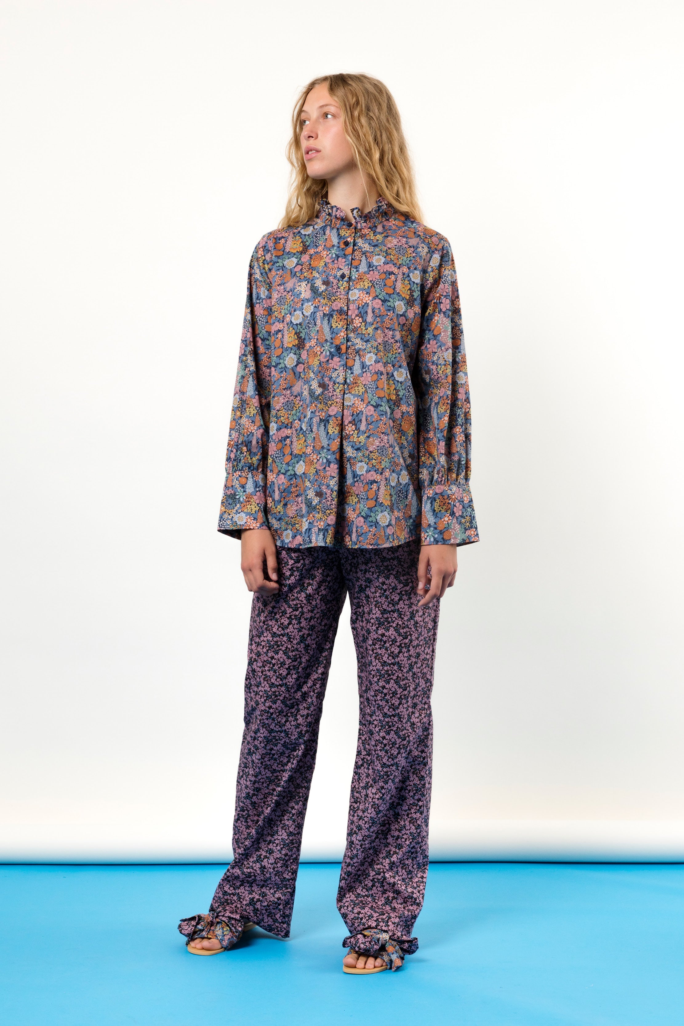 Woman wearing long sleeved flower patterned shirt and trousers