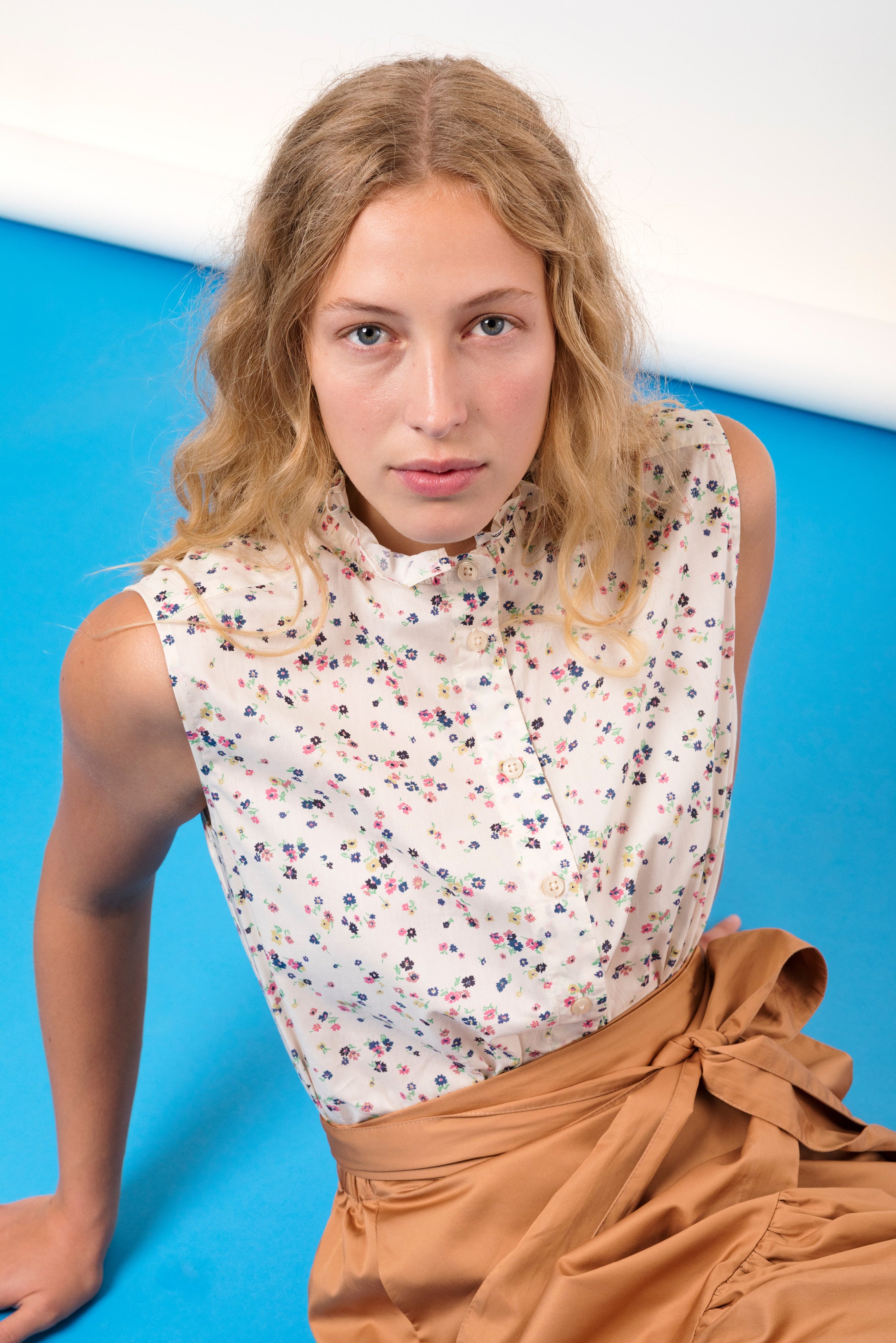 Woman in short sleeved top with flower pattern and brown wrap skirt