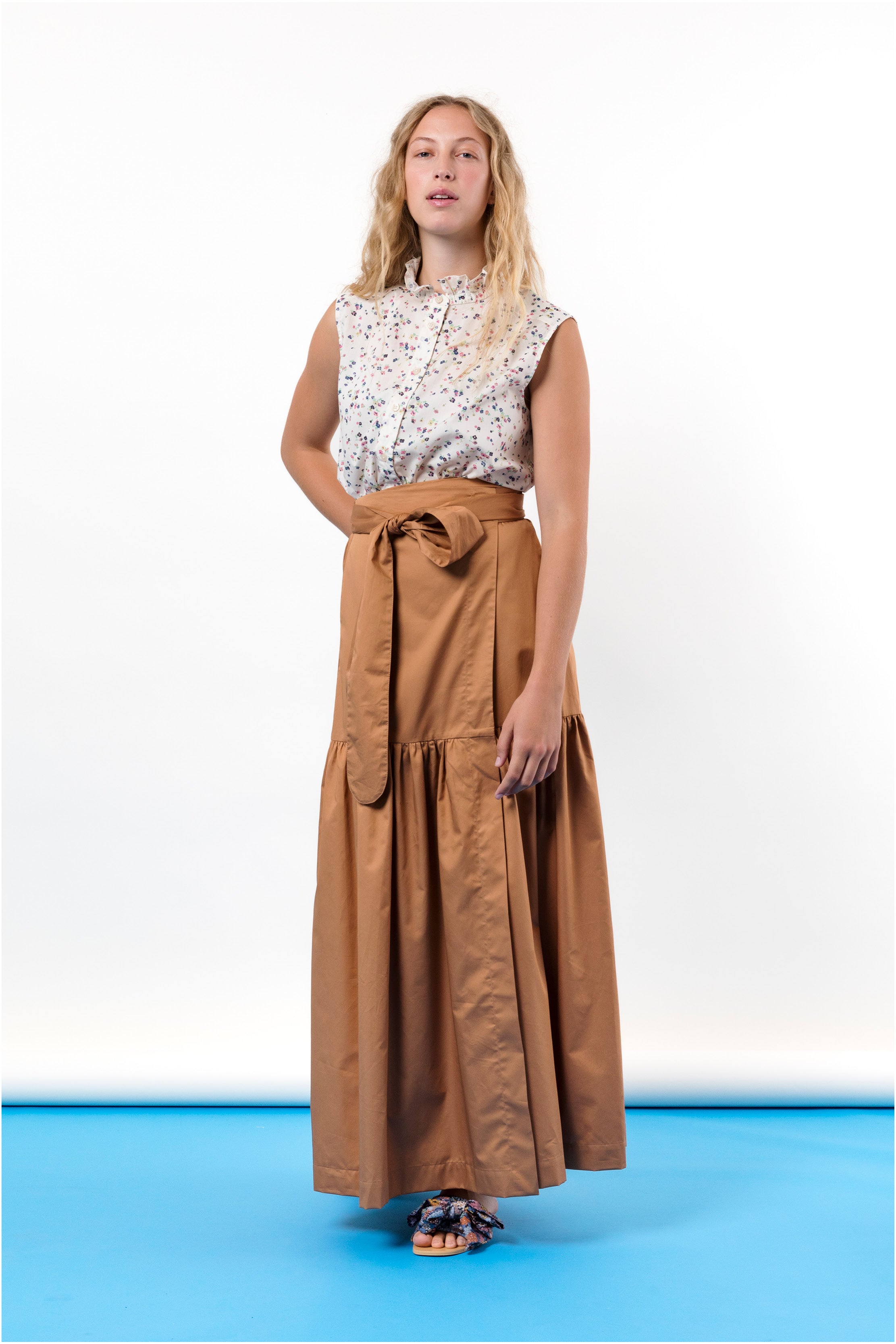 Woman in biscuit brown wrap skirt and sleeveless flower patterned shirt