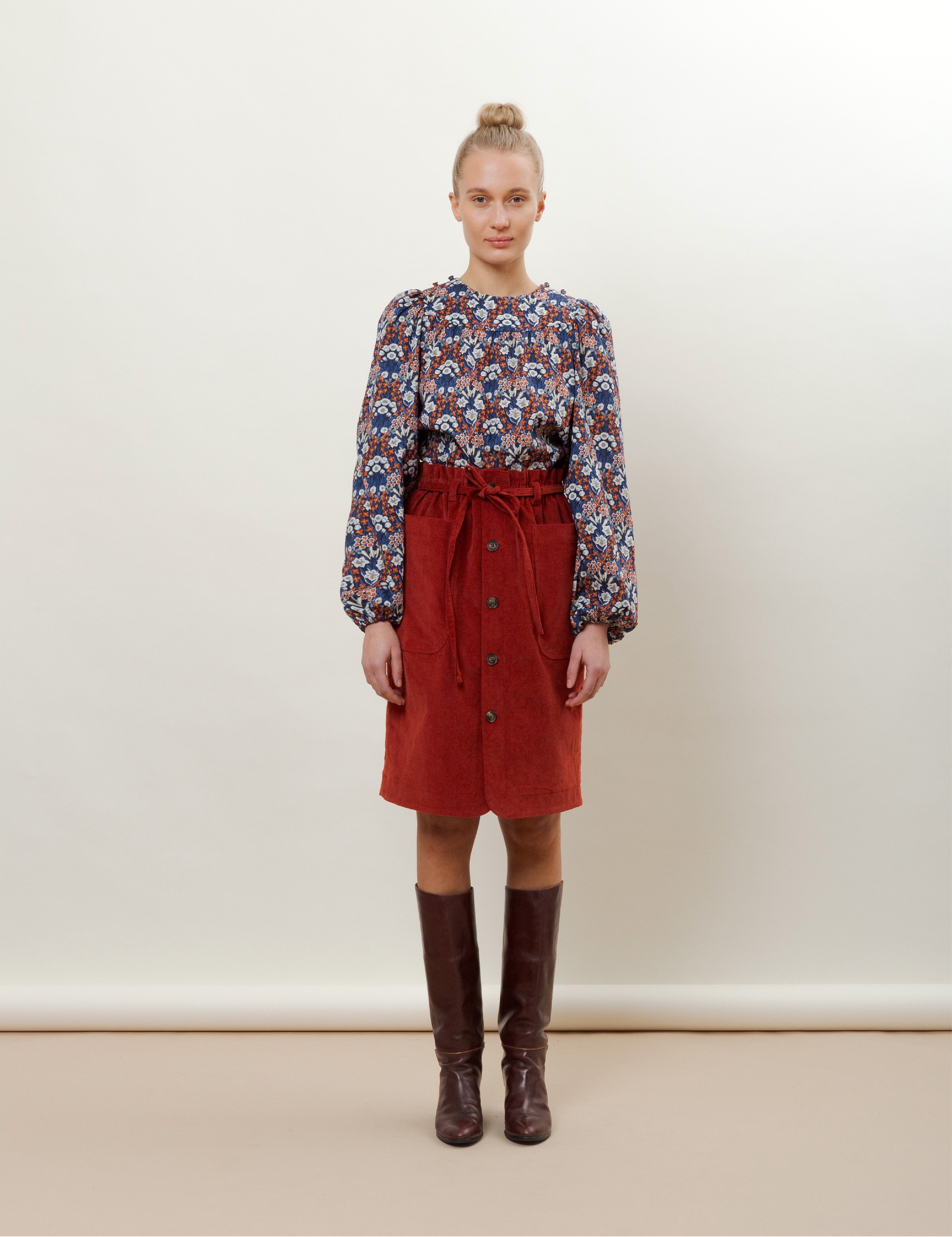 Woman in red corduroy skirt and red blue and white flower patterned blouse