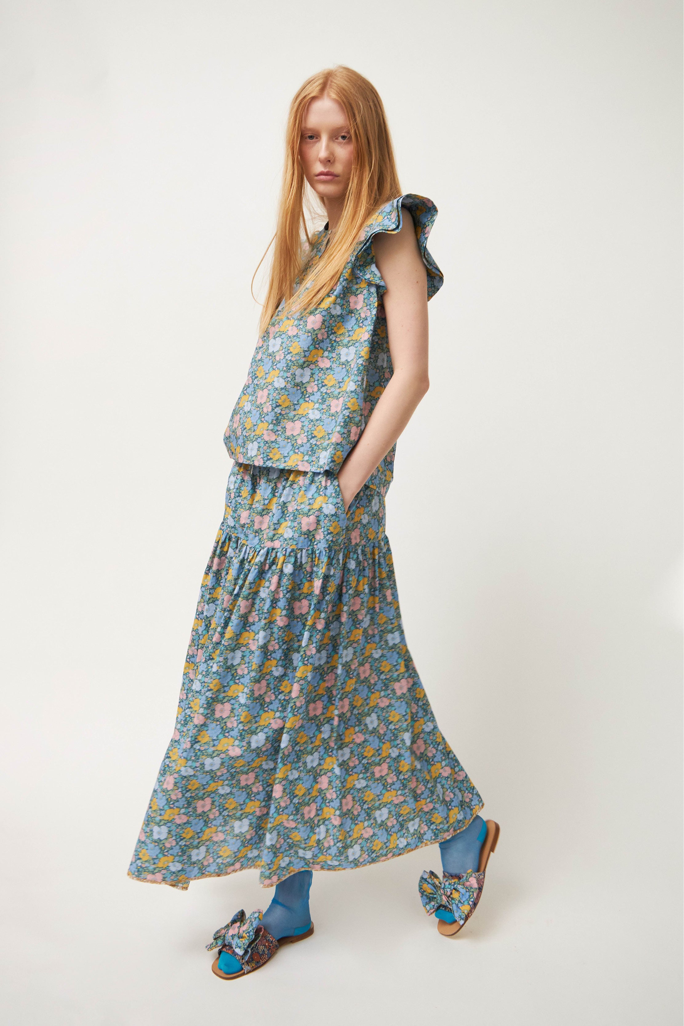 Woman in top with frills and maxi skirt with multi colored  flower pattern
