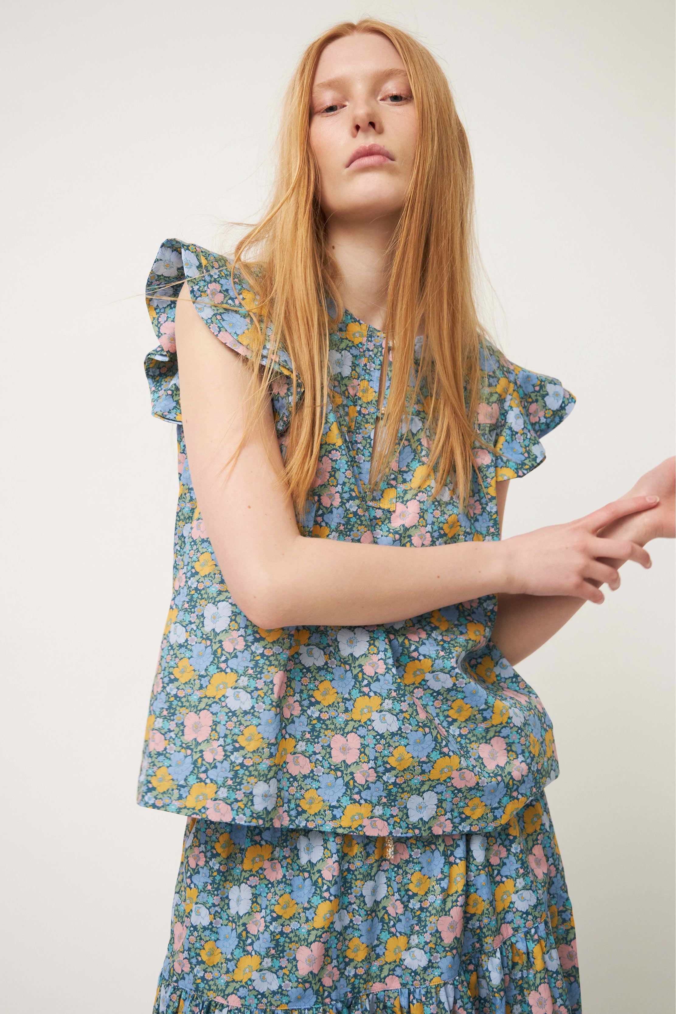 Woman in green sleeveless blouse and skirt with flower pattern and frills