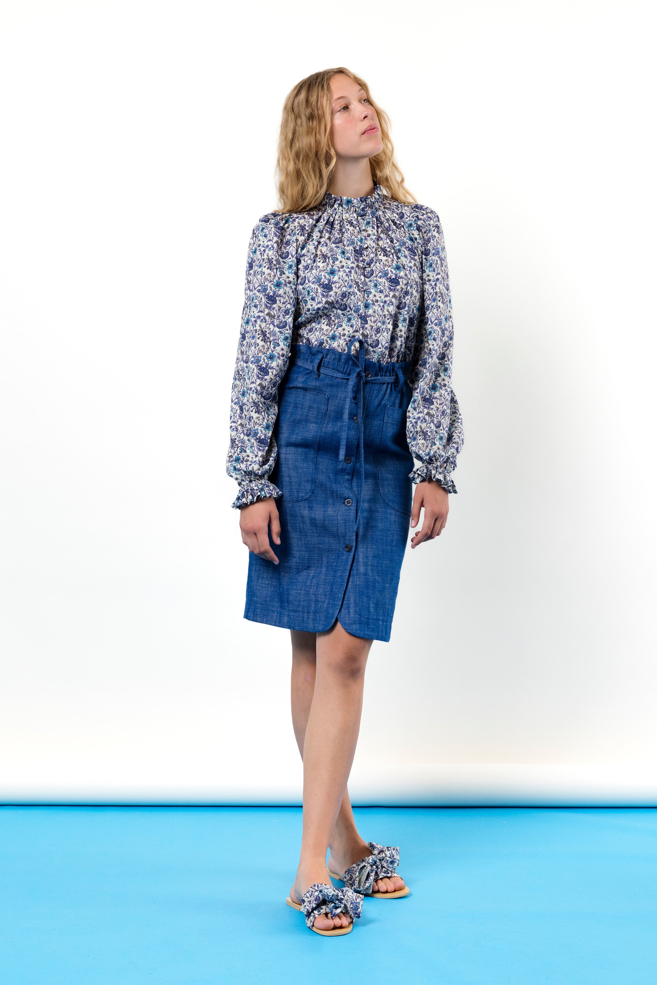 Woman with long sleeved shirt with blue flowers and blue skirt