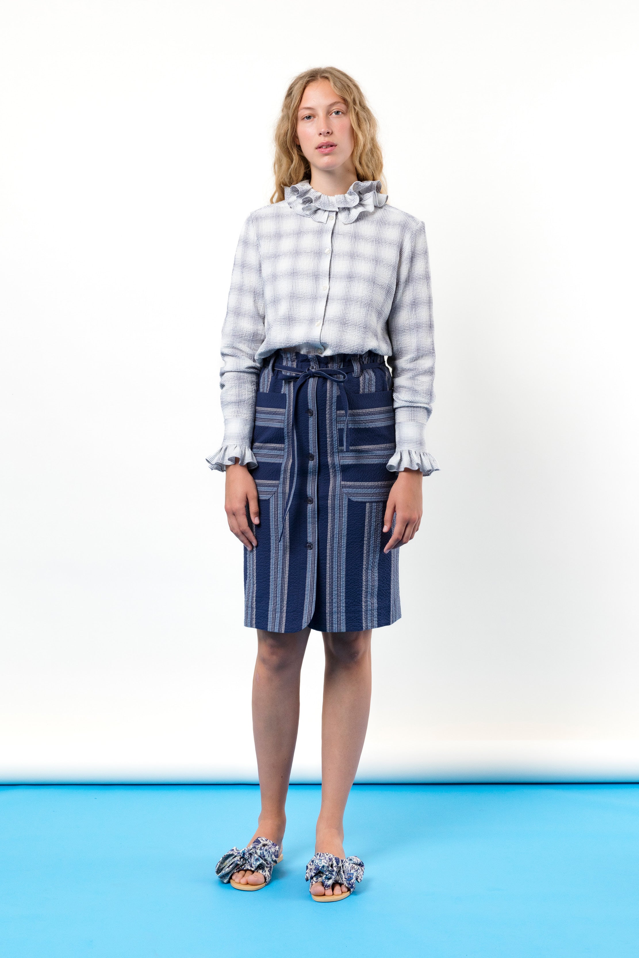 Woman in checked blouse with frills and striped skirt