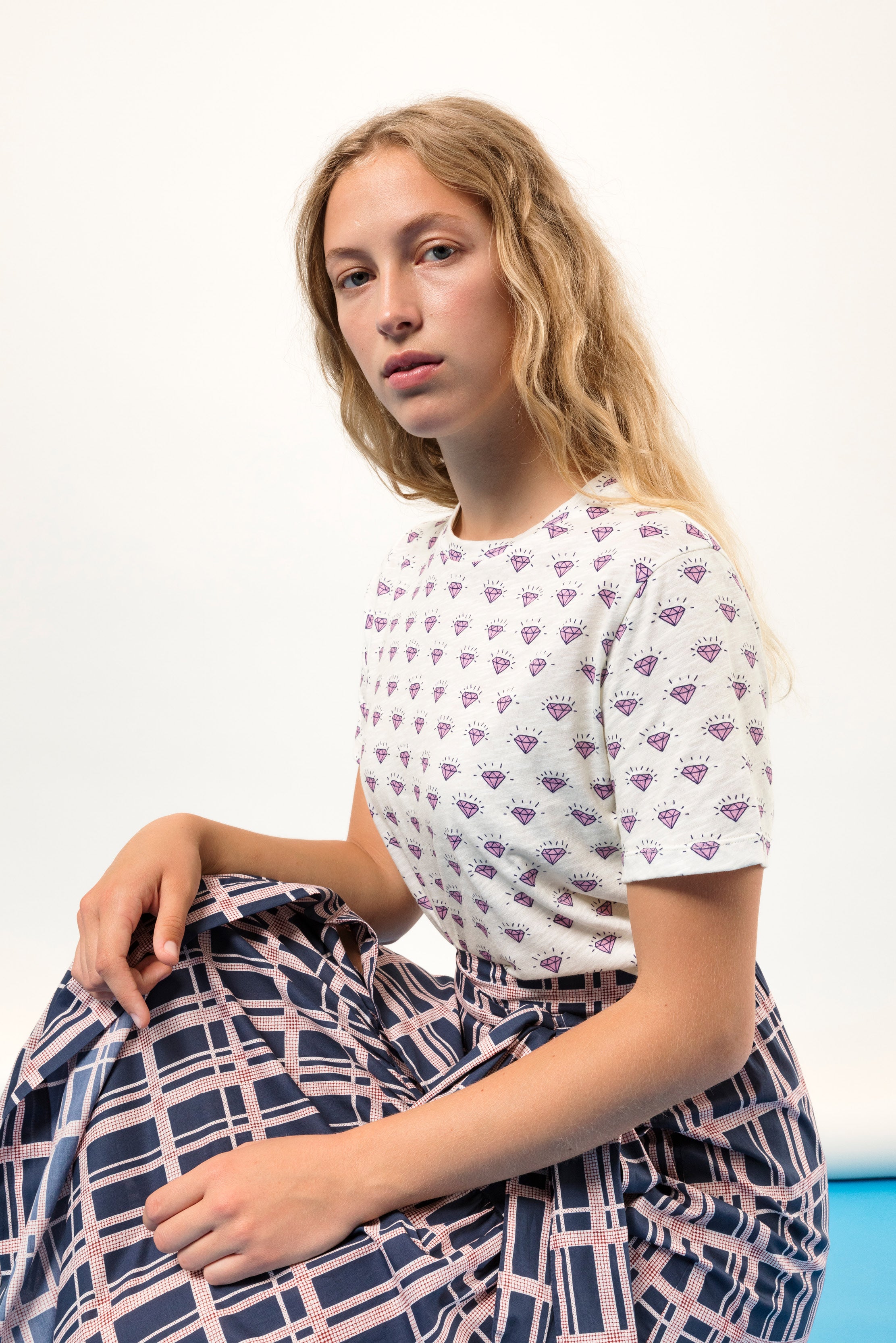 Woman in short sleeve white t-shirt with diamond pattern and checked skirt