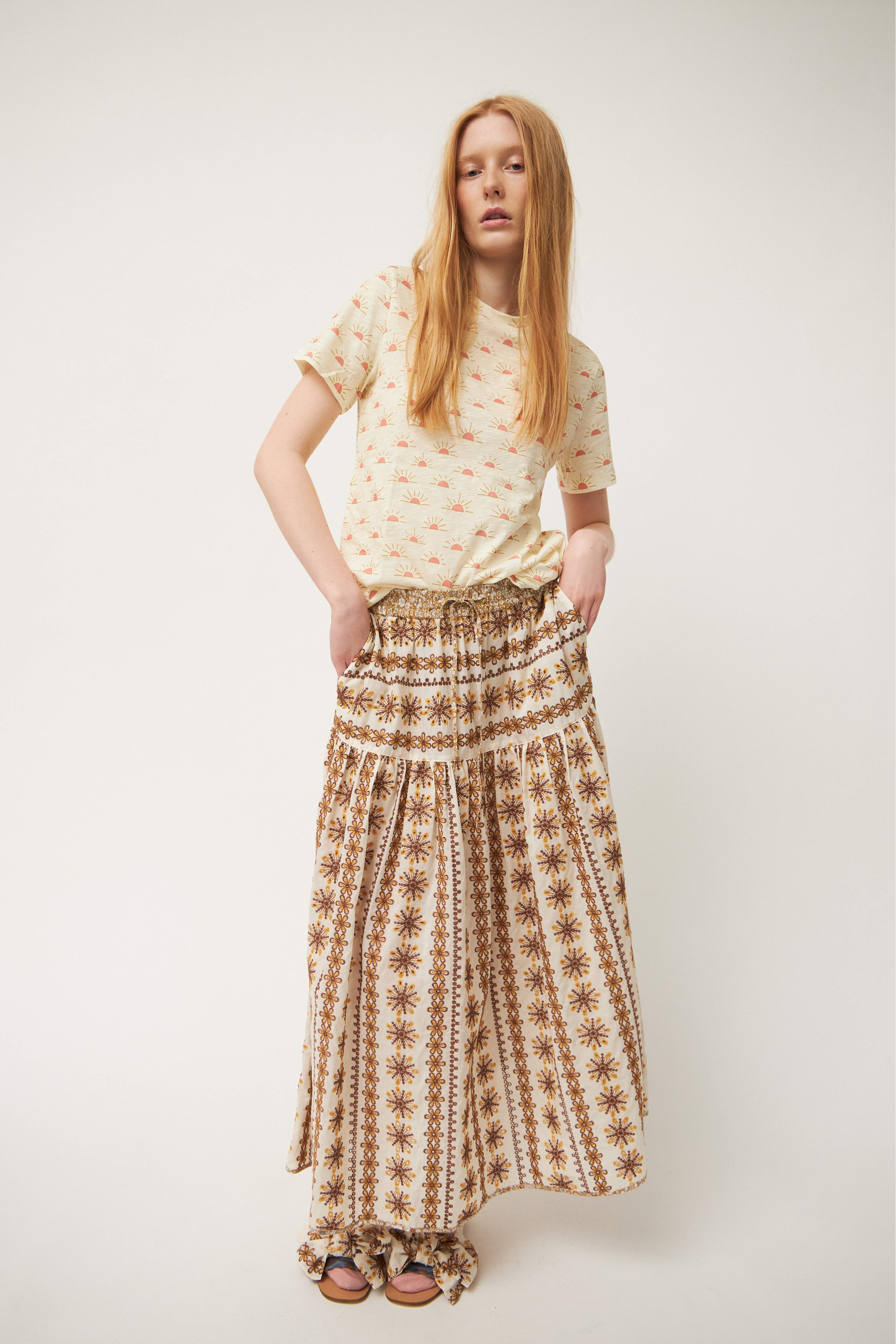 Woman in short sleeve white t-shirt with sunrise pattern and maxi skirt with laced pattern