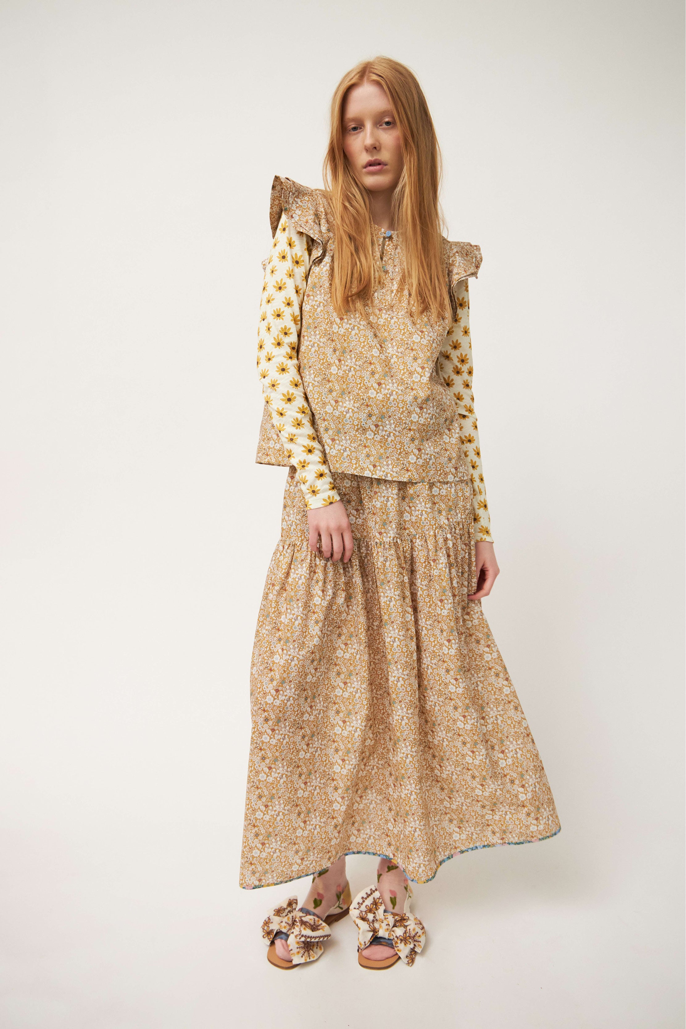 Woman in top with frills and maxi skirt with beige and white flower pattern