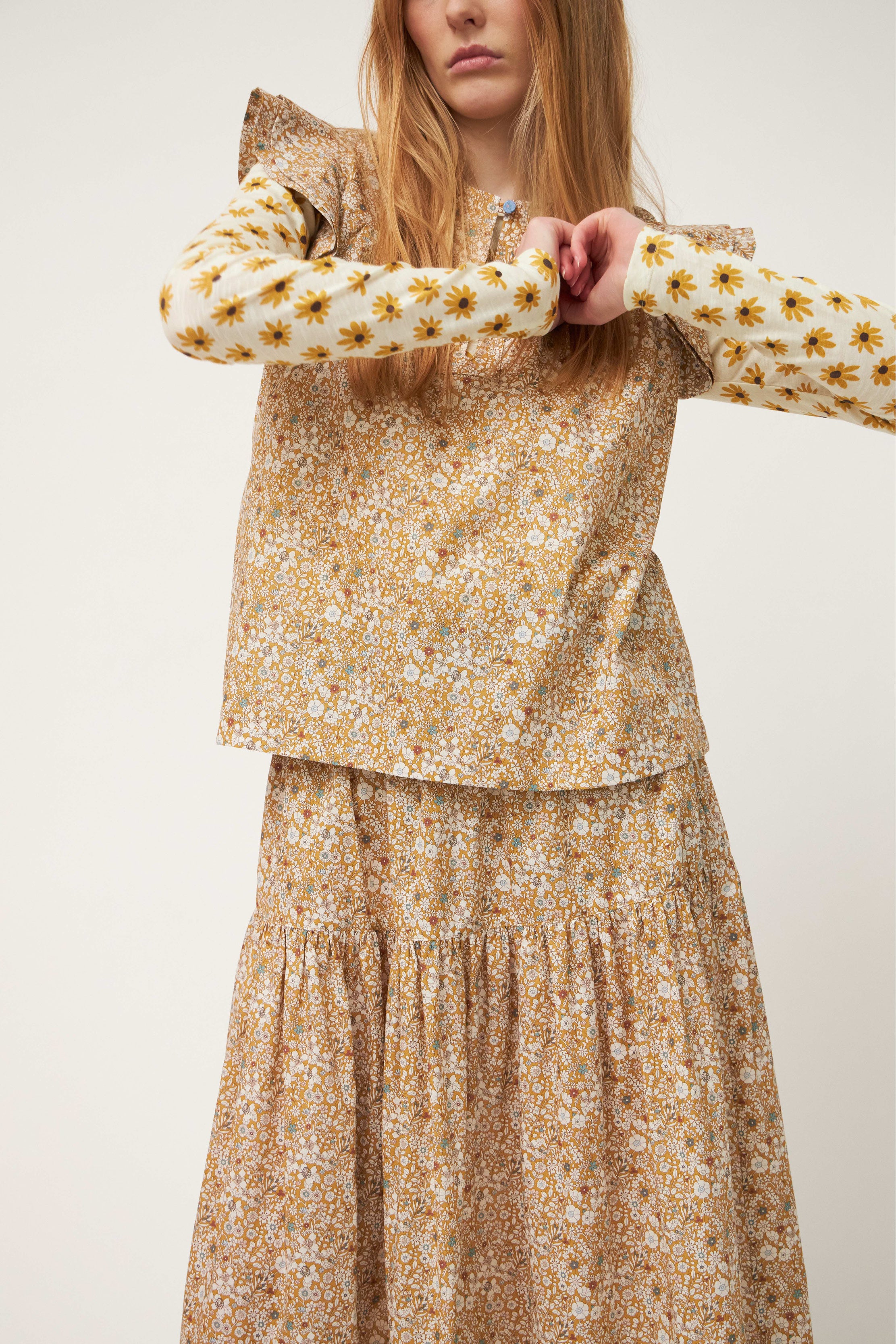 Woman in top with frills and maxi skirt with beige and white flower pattern