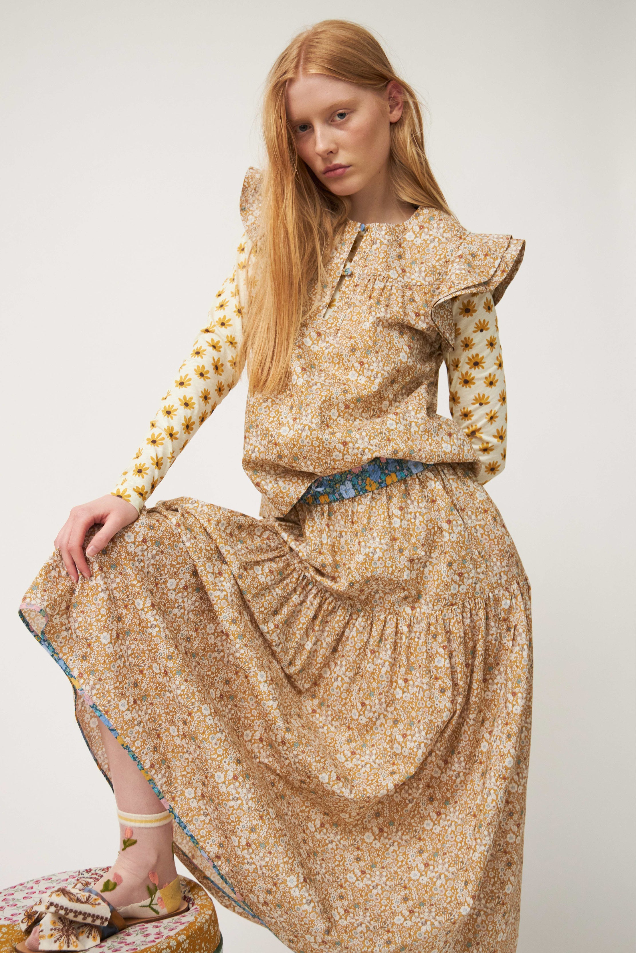 Woman in short sleeved brown blouse and skirt with flower pattern and sandals with bows