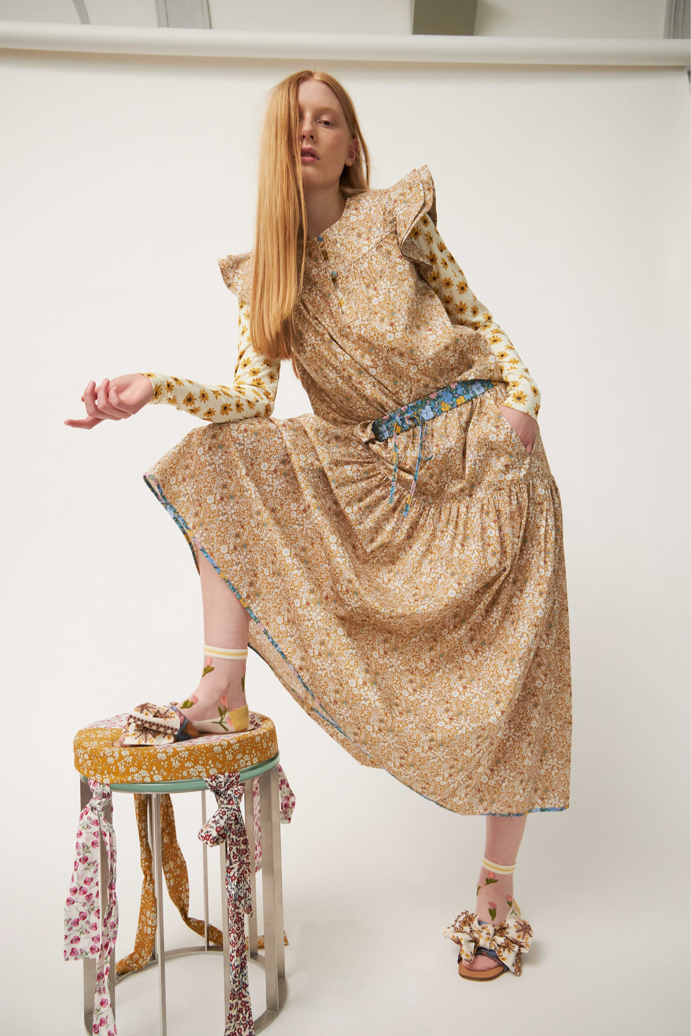 Woman in top with frills and maxi skirt with beige and white flower pattern