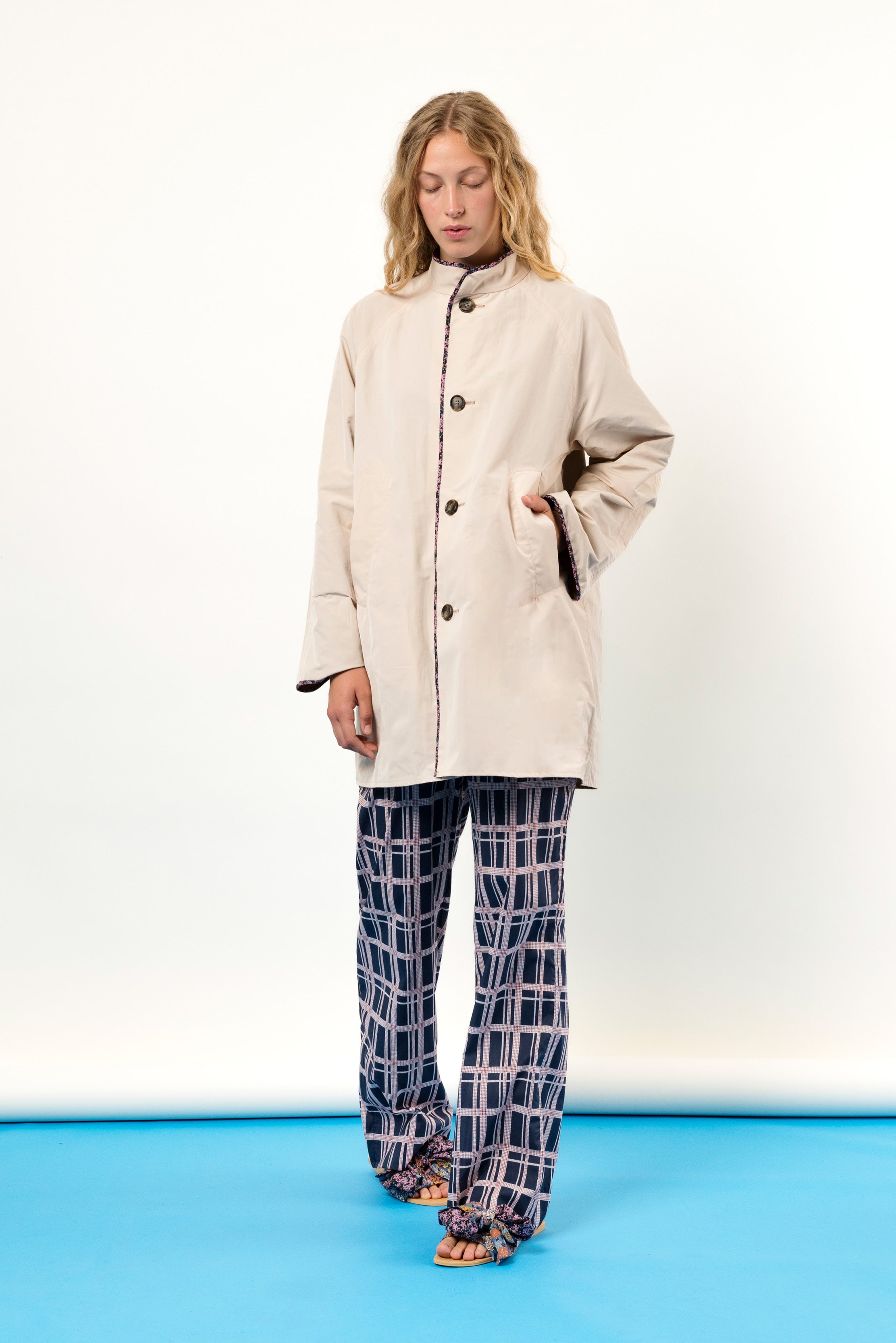 Blonde woman in white jacket with pockets and checked pants