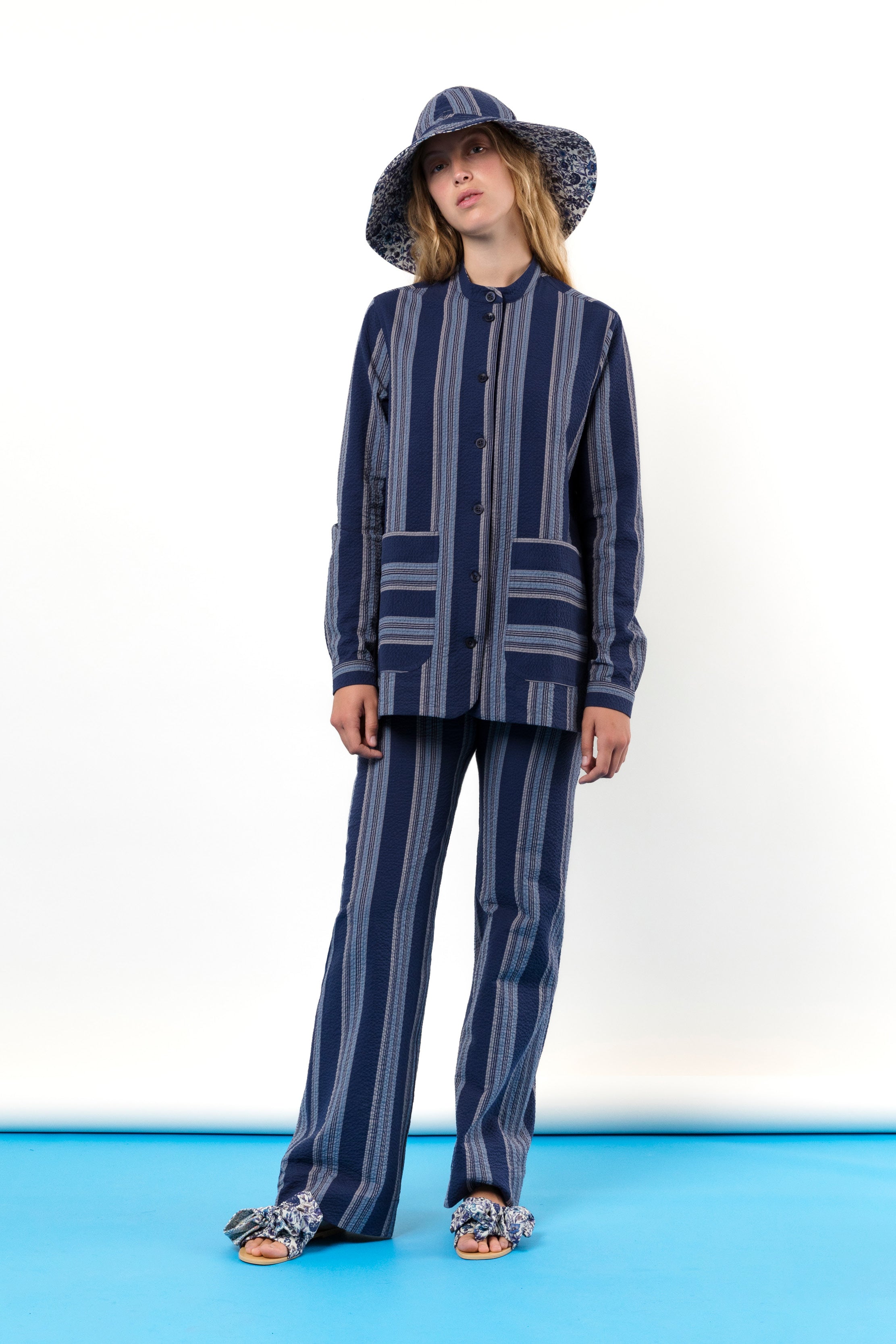 Woman in Blue and white striped hat and jacket with pockets and buttons, striped trousers and sandals with bows
