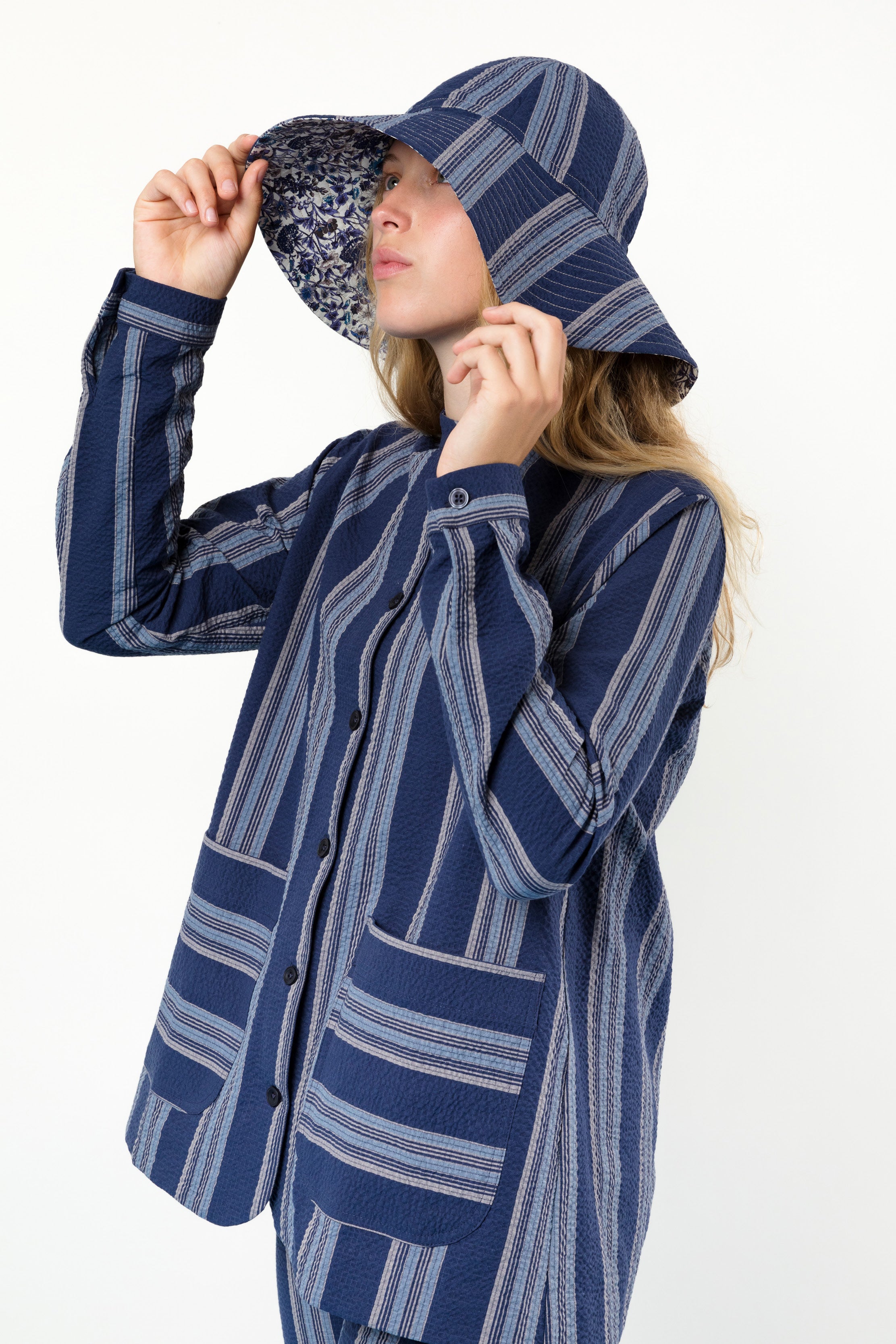 Woman in blue and white striped hat and jacket with pockets and buttons