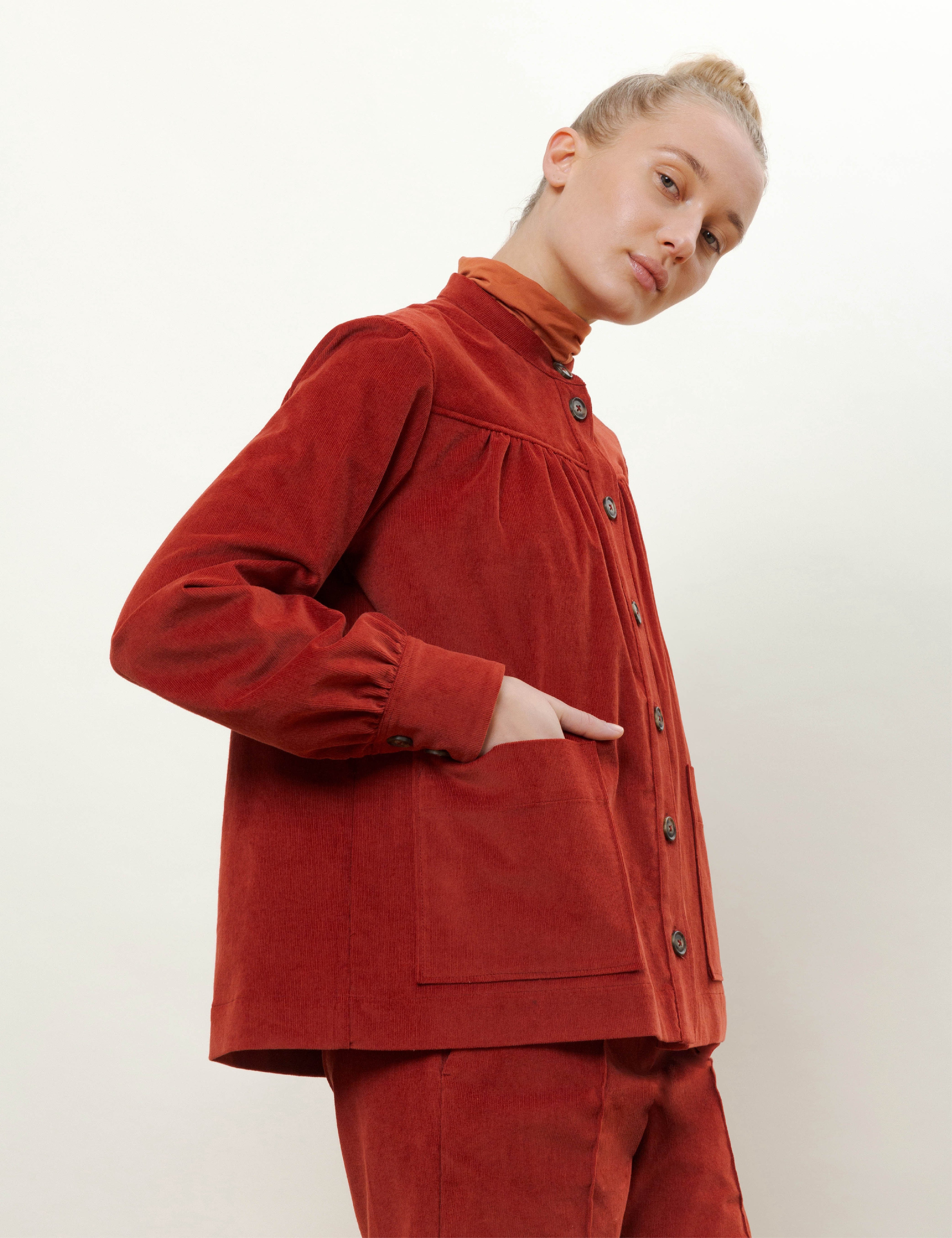 Woman in red corduroy pants and jacket with pockets and buttons