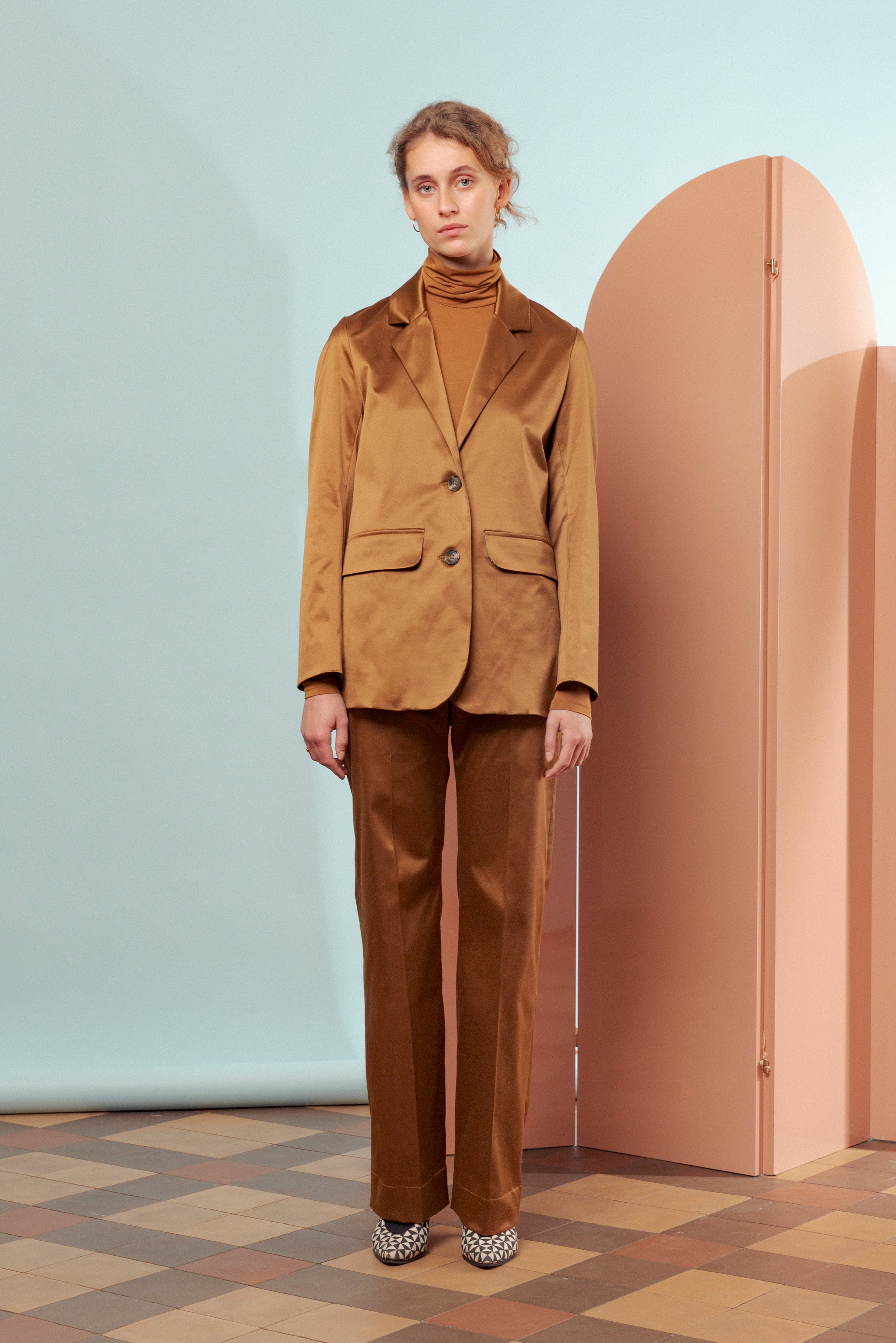 Woman in brown pants and jacket with buttons and pocket and brown roll neck