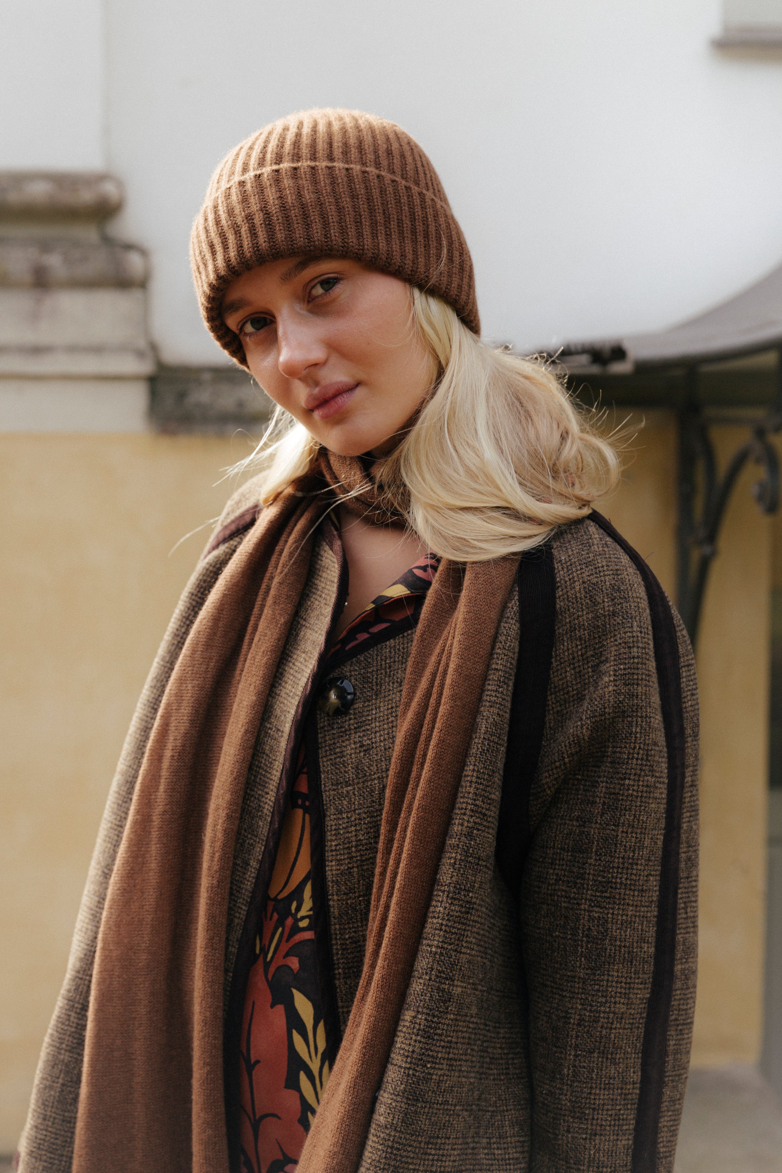 Blonde woman in brown coat, brown cashmere beanie and brown cashmere scarf