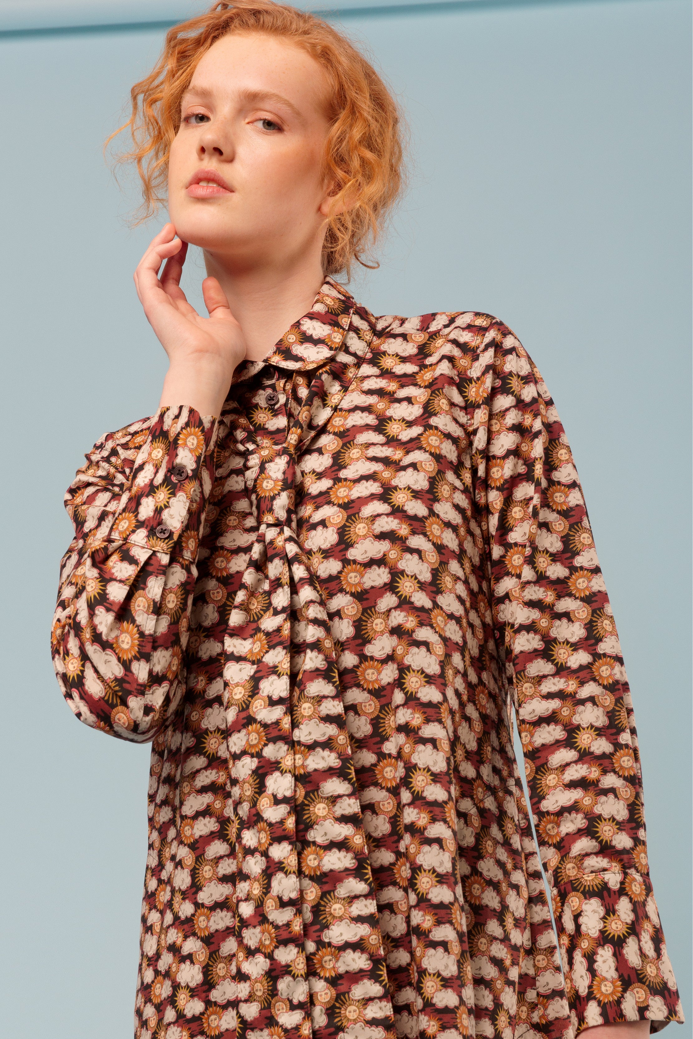 Woman wearing cotton shirt dress with sun and clouds pattern and long sleeves