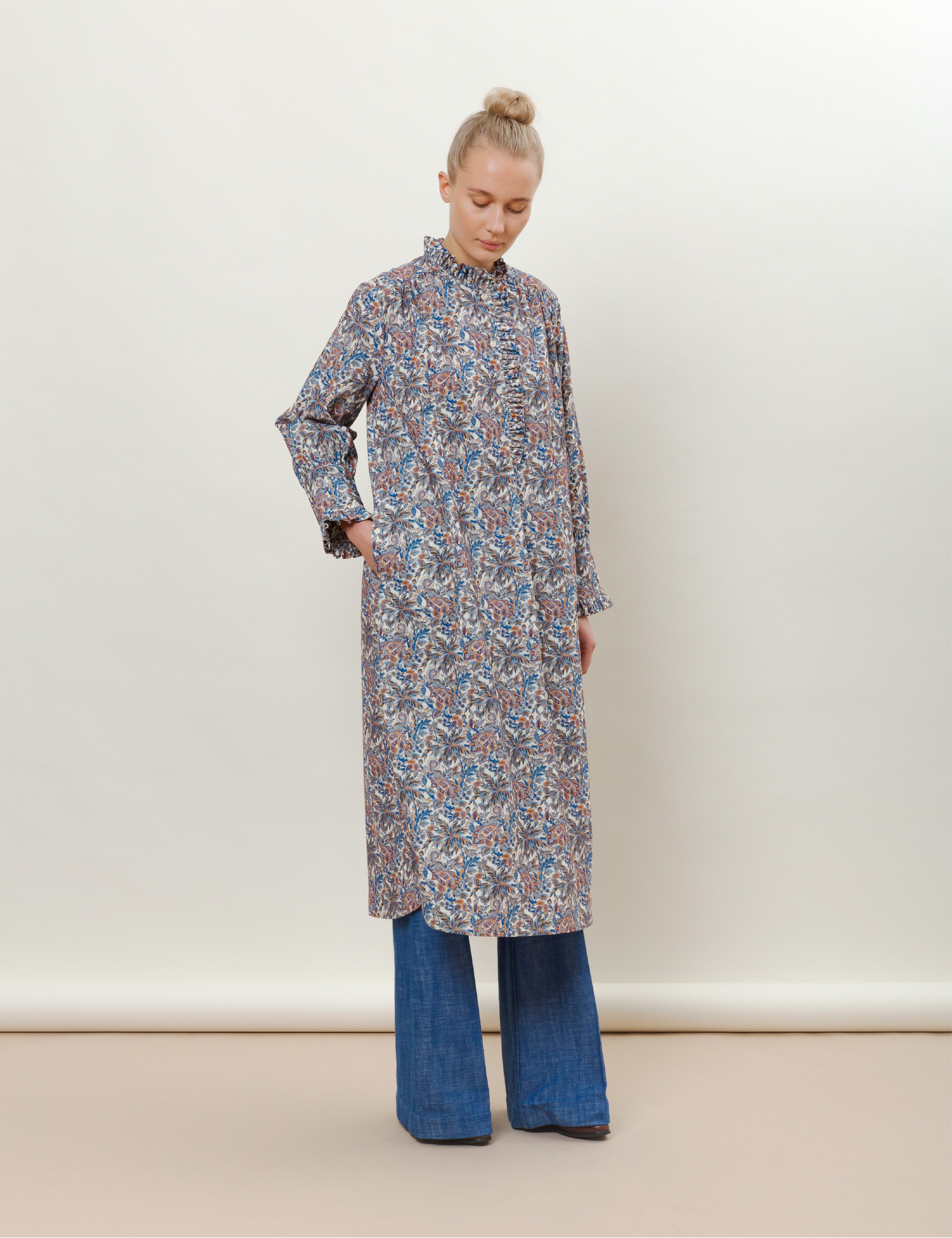 Woman in long-sleeved floral print dress with ruffled collar and wide-leg blue jeans