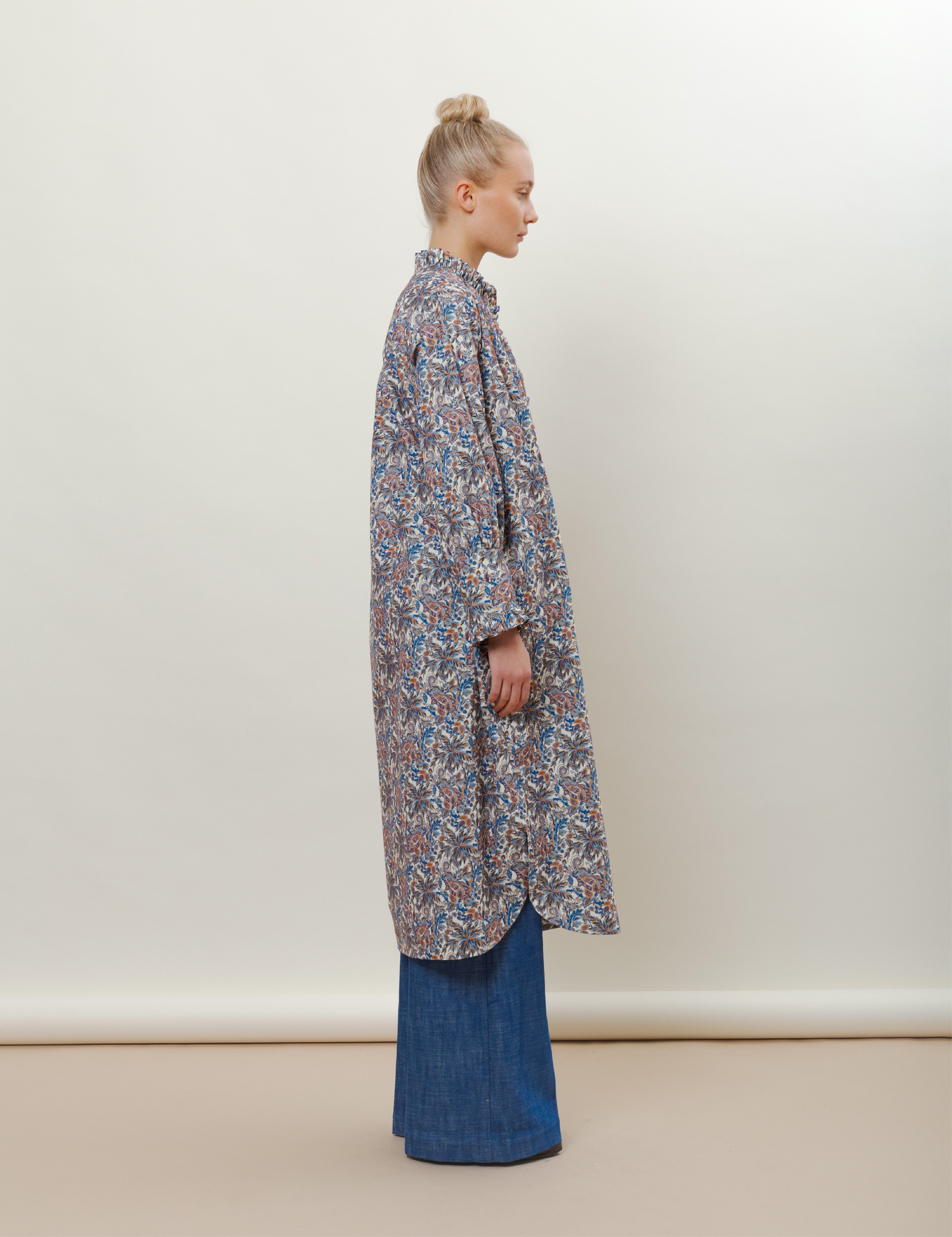 Woman in long-sleeved floral print dress with ruffled collar and wide-leg blue jeans