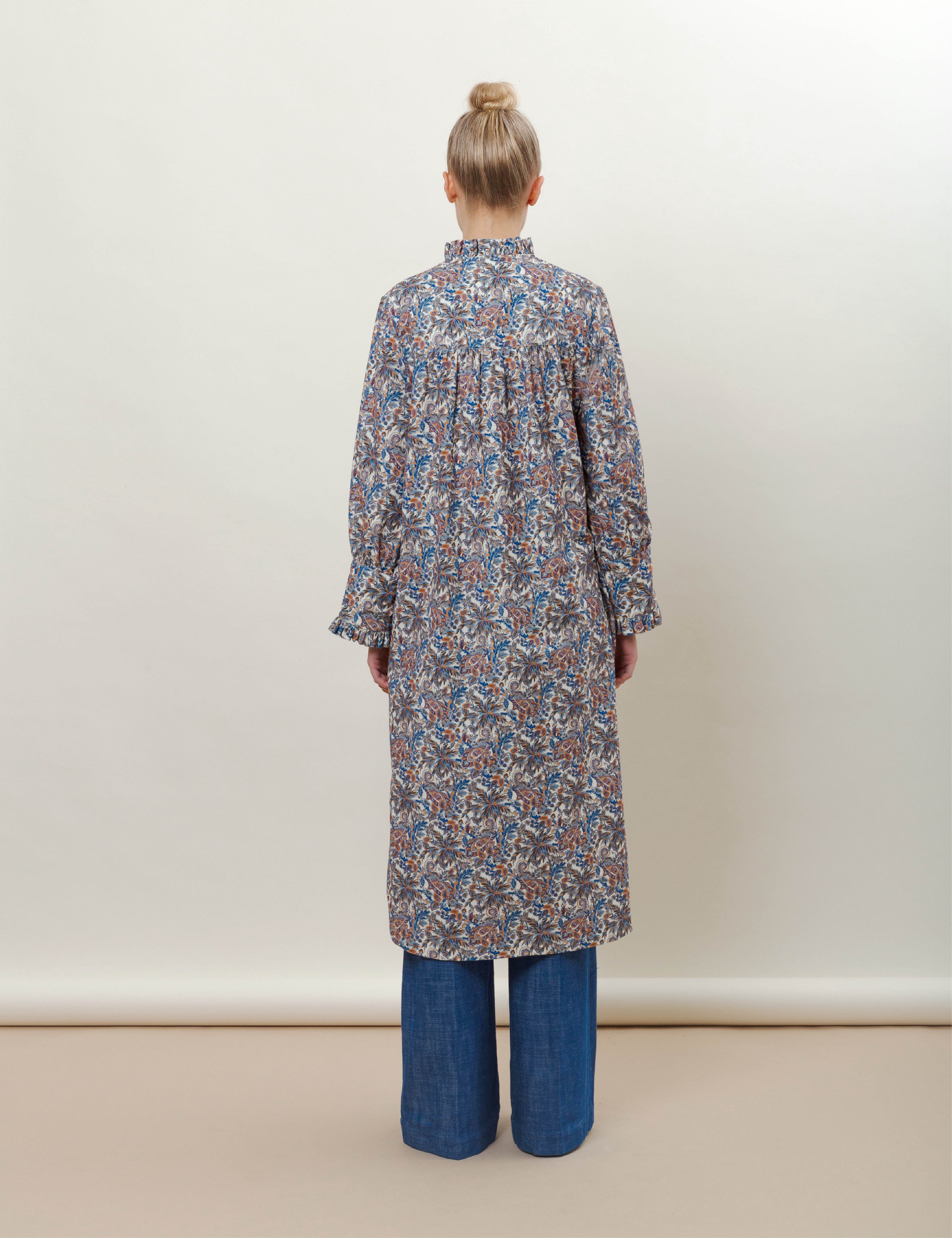 Woman in long-sleeved floral print dress with ruffled collar and wide-leg blue jeans