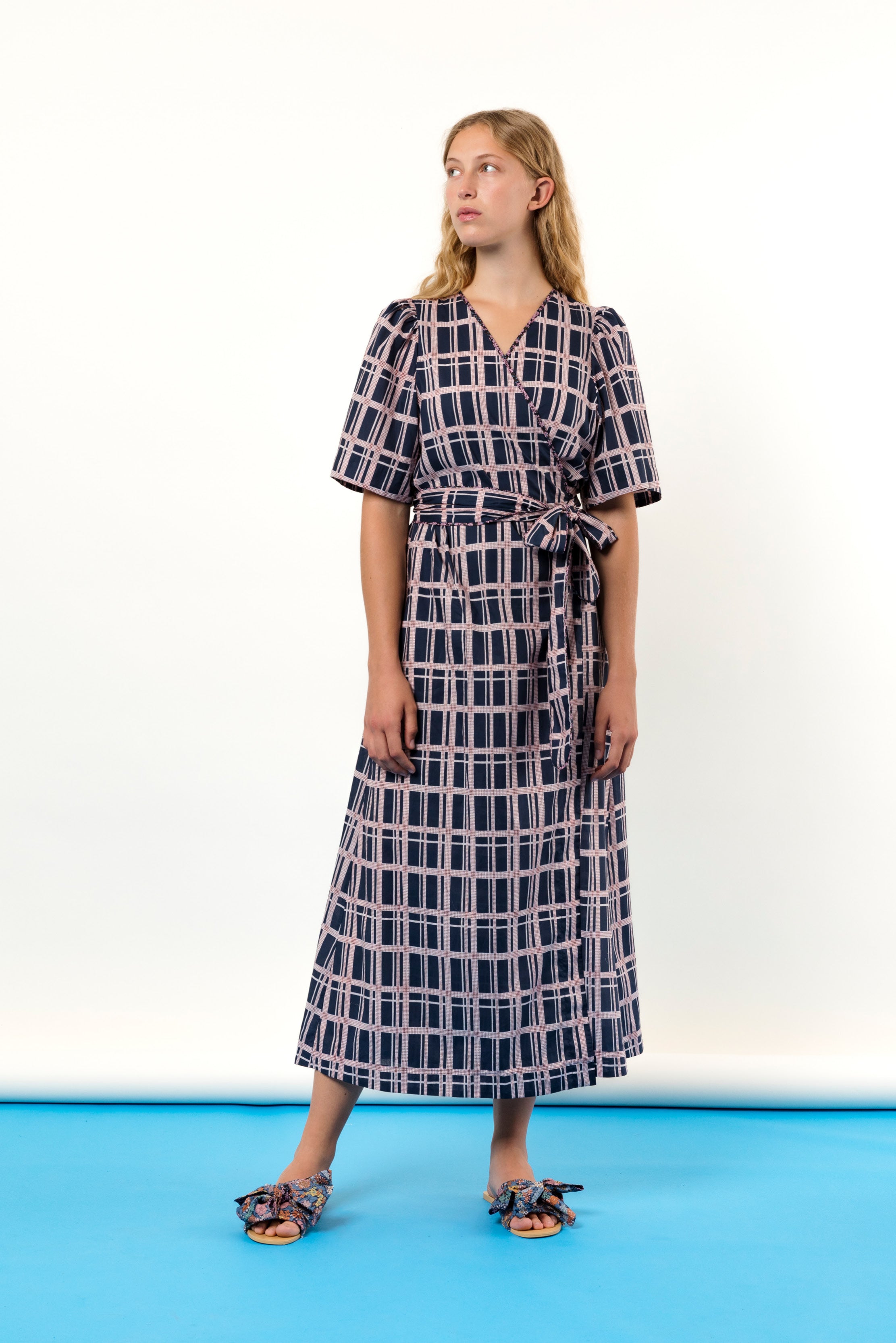 Woman in black and pink checked wrap dress in Liberty cotton with short sleeves and sandals with bows