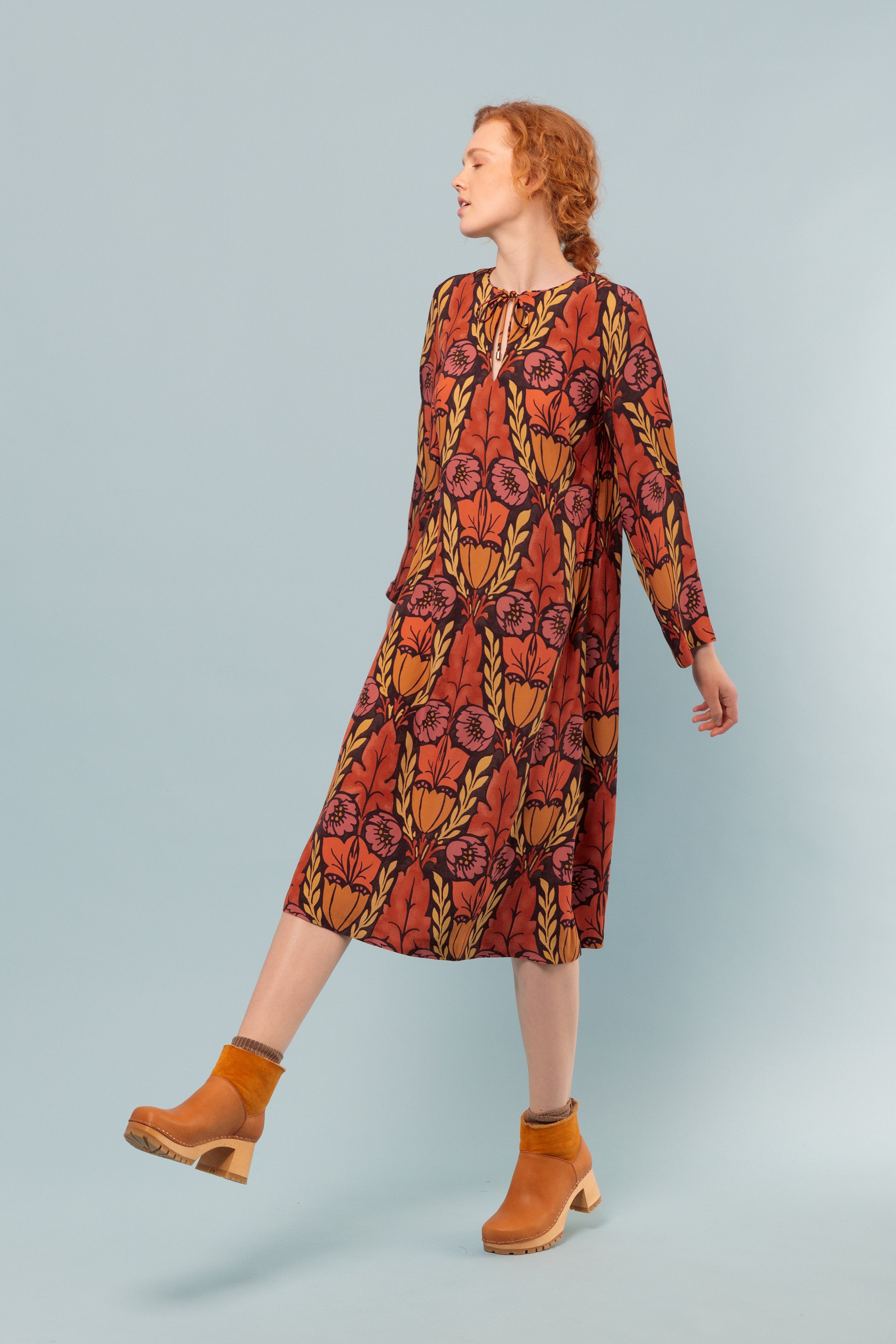 Woman in midi long sleeved viscose dress with large flower print in pink, orange and yellow
