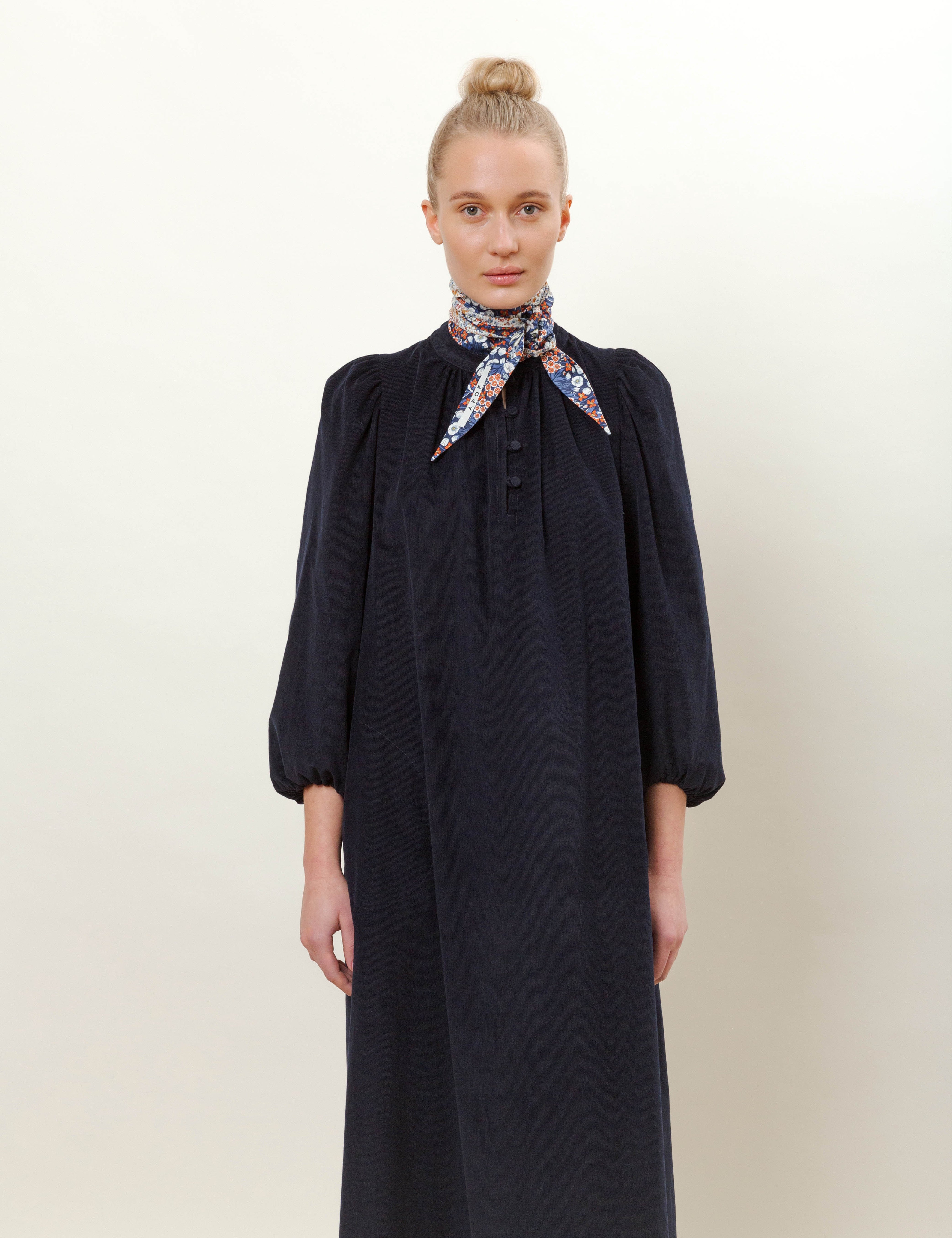 Woman in long navy blue corduroy dress with flower patterned scarf
