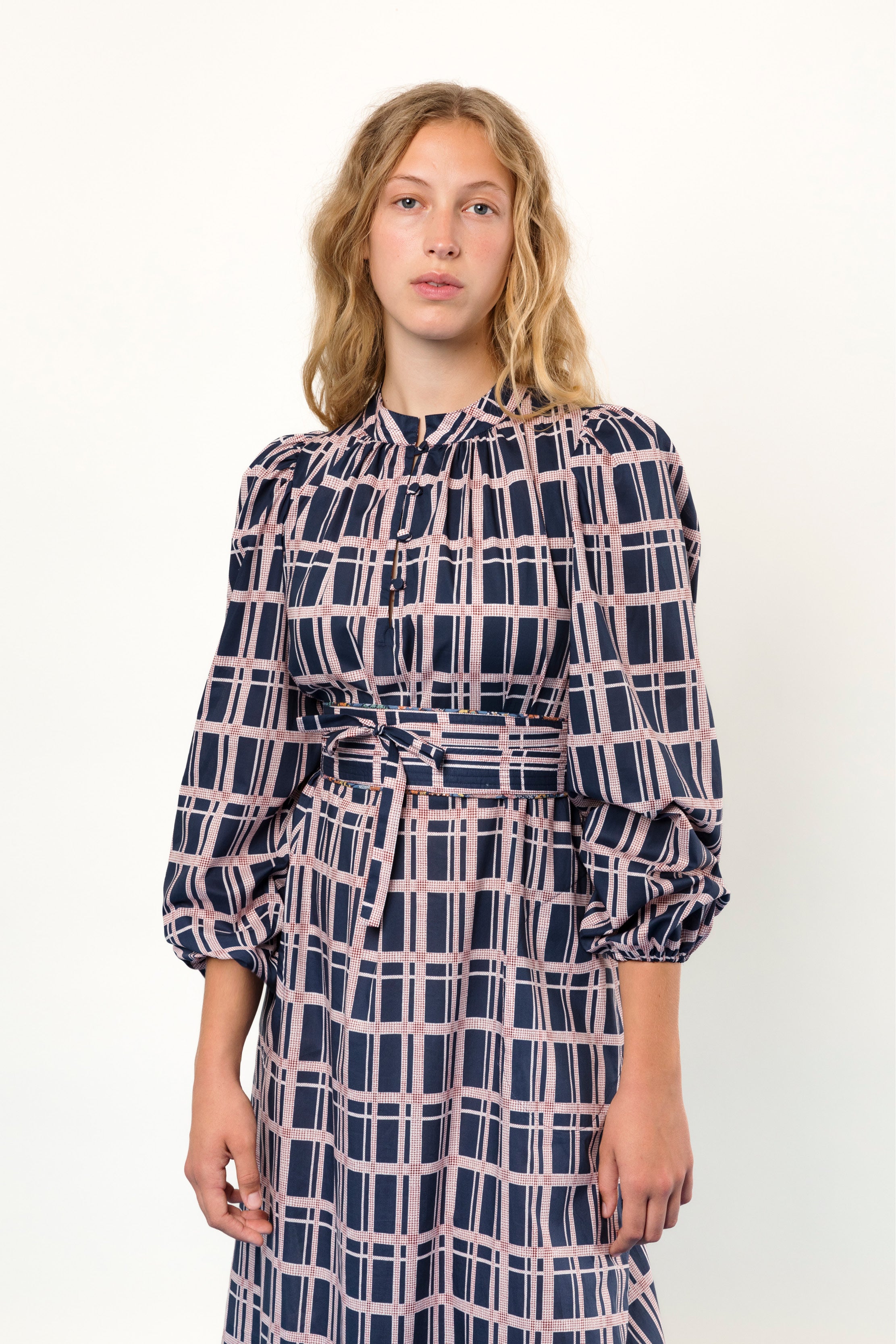 Woman in long Liberty cotton dress with pink and blue check print, long puffed sleeves and belt