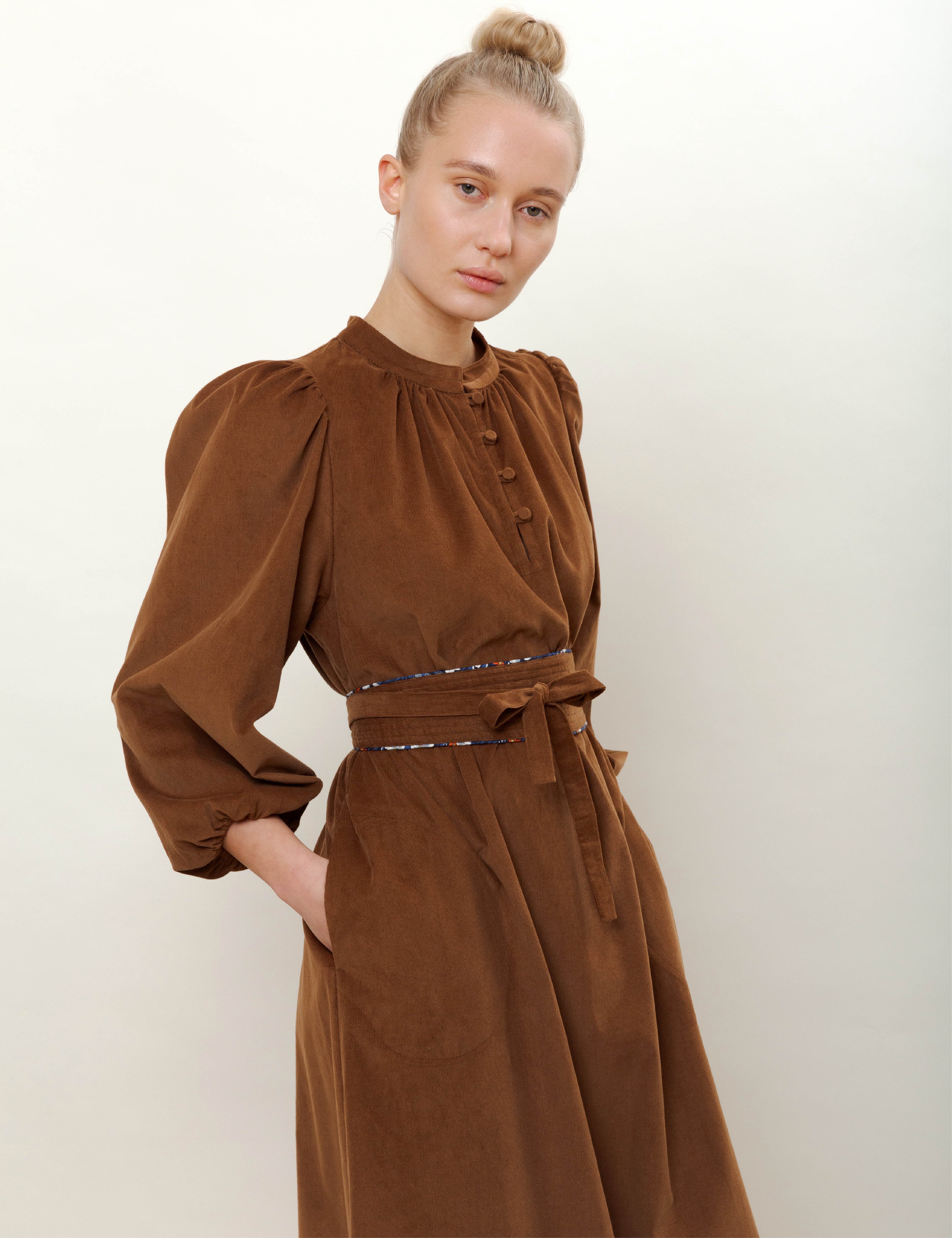 Woman in long sleeved brown corduroy dress with belt