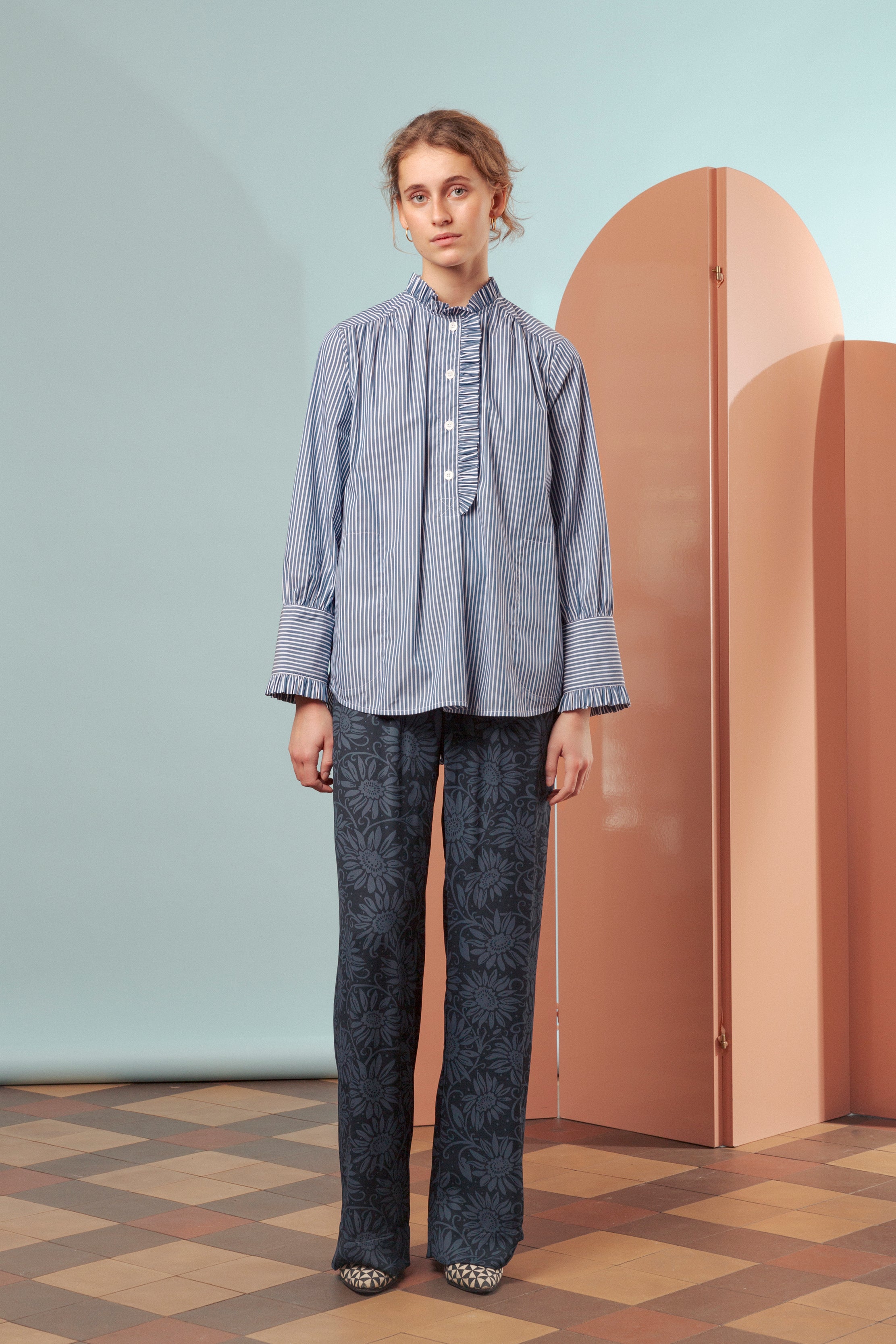 Woman in blue and white striped frill shirt and blue trousers