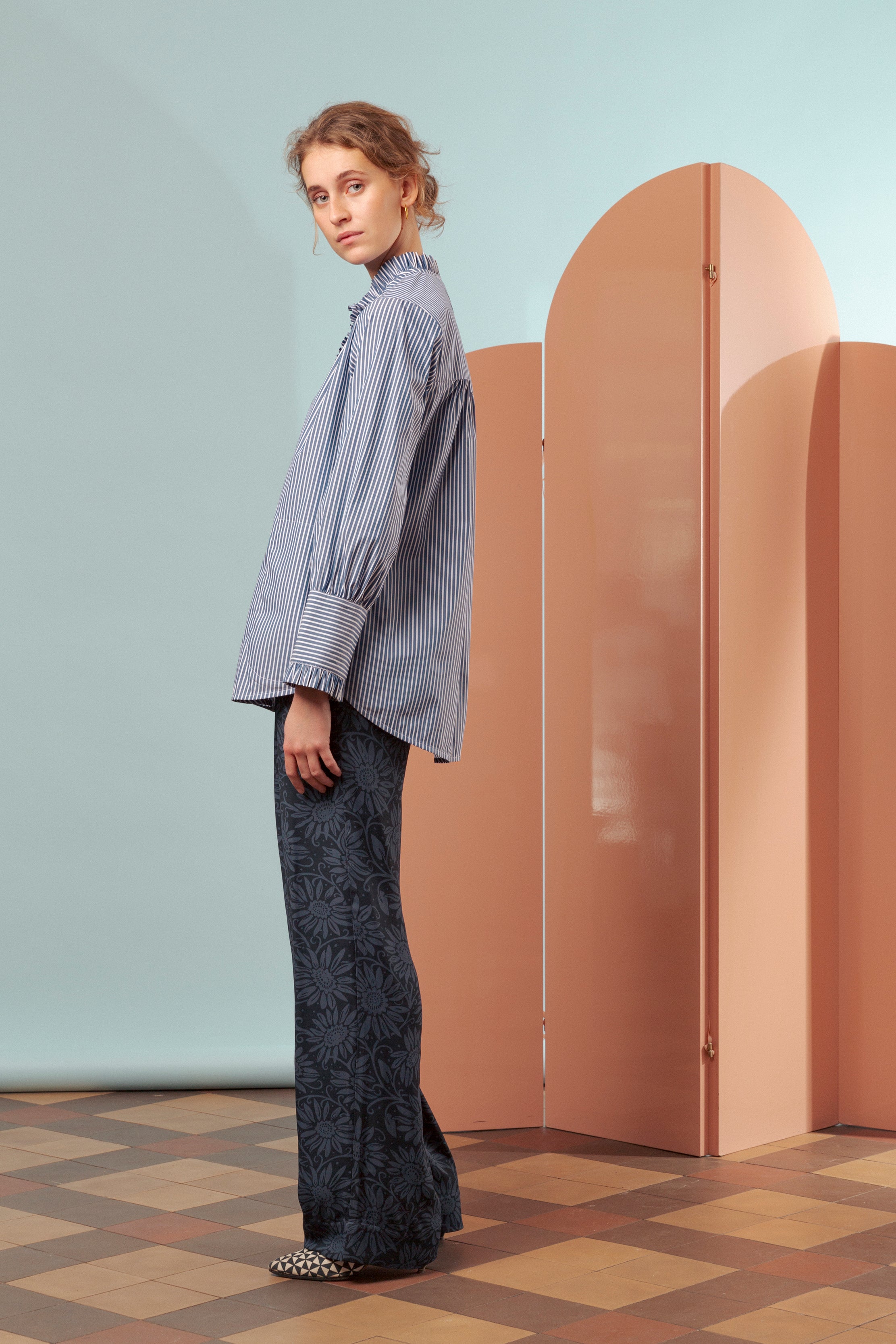 Woman in blue and white striped frill shirt and blue trousers